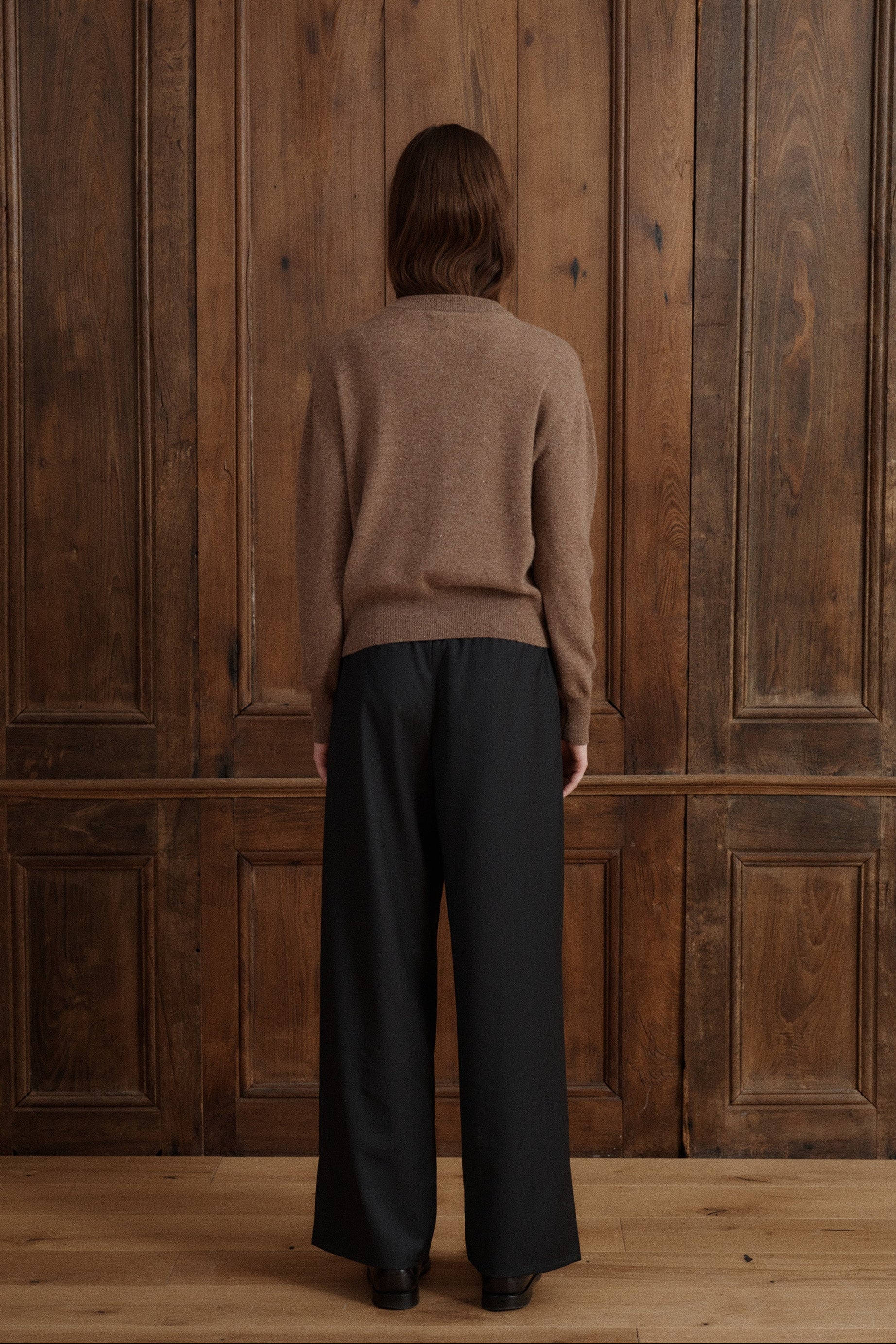 Female model posing in a speckled light brown cardigan made in soft cashmere with slouchy details to create a relaxed silhouette. Paired with dark grey elastic waist wool trousers and black loafers. - VIR VITA
#color_toastedwalnut