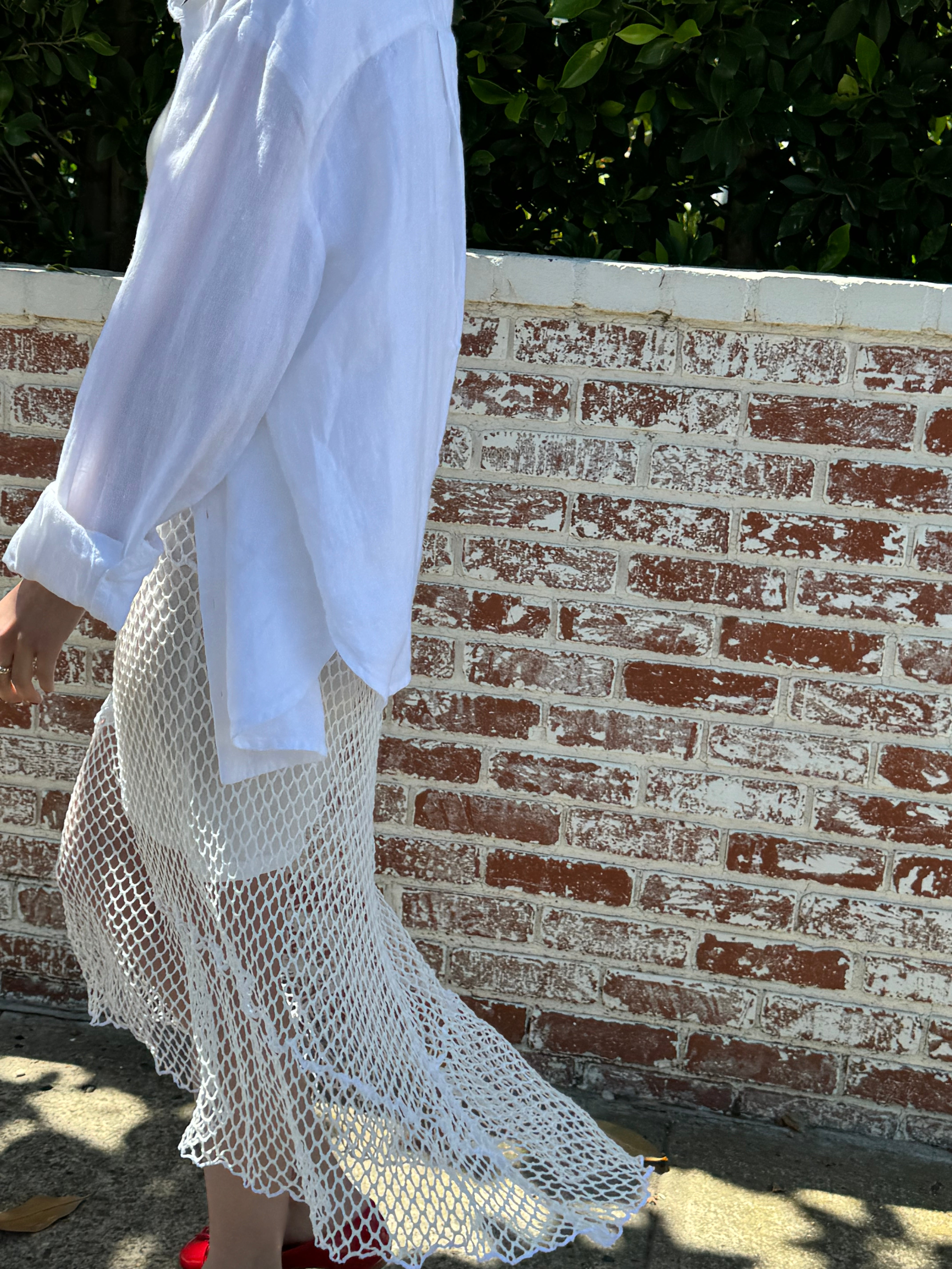 Female model wearing an exquisite crochet skirt featuring an asymmetrical silhouette in white paired with a linen long sleeve shirt in white - VIR VITA
#color_coconut
