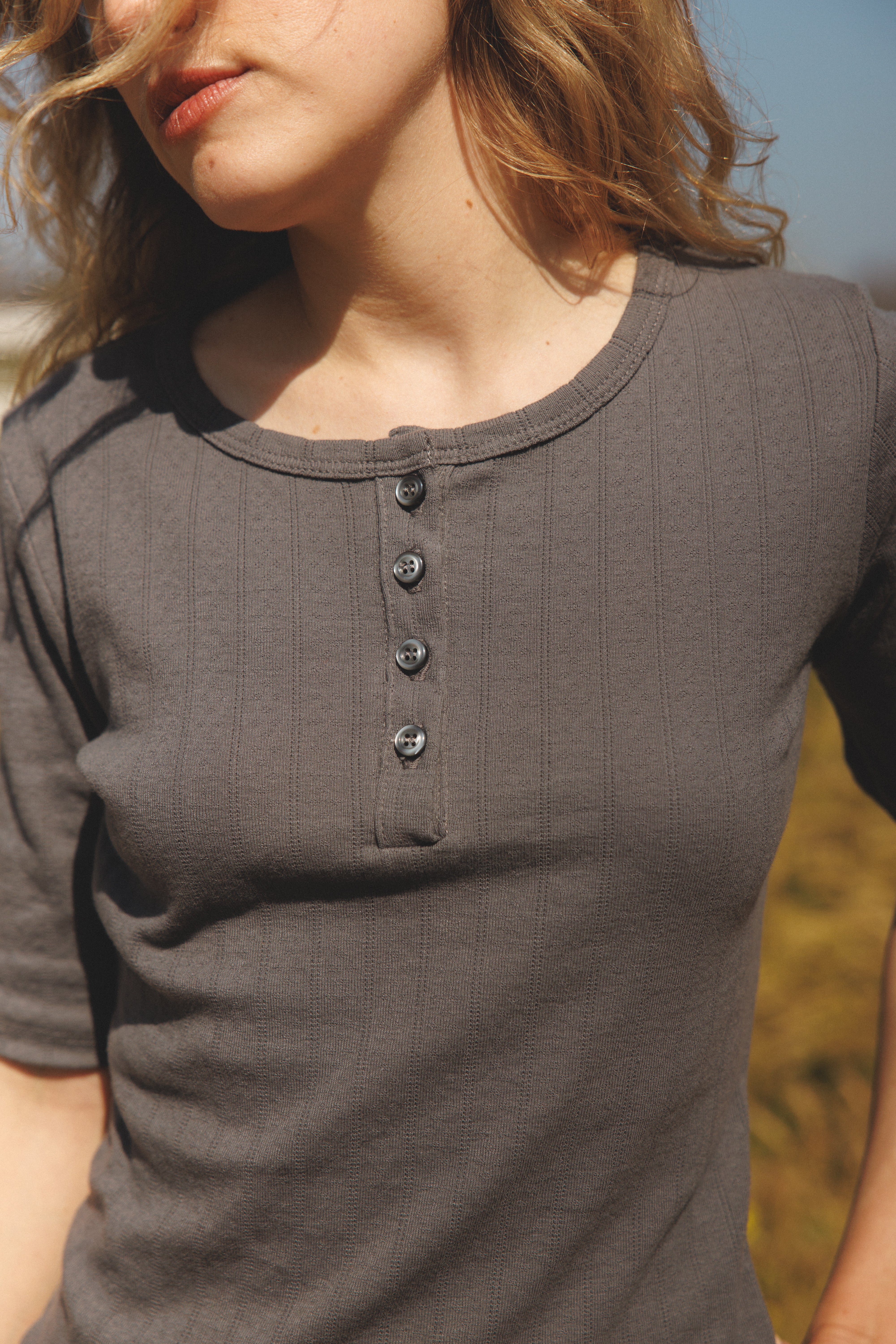 Female model wearing a grey henley quarter sleeve cotton pointelle top with matching buttons - VIR VITA
#color_stone grey