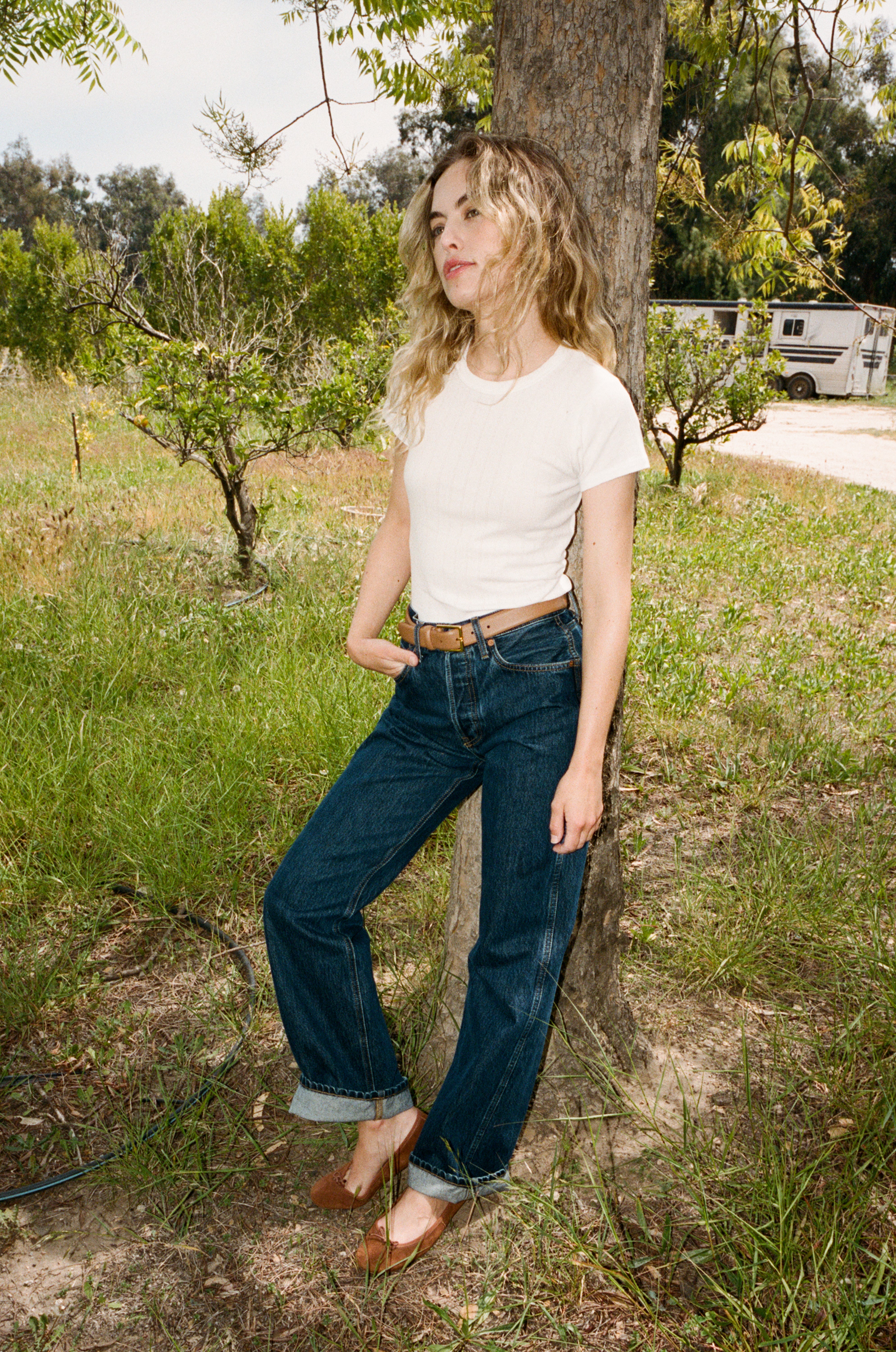 Female model wearing the signature 100% cotton Pointelle Tee with a classic crewneck neckline in white with a brown belt, blue jeans, and brown flats - VIR VITA #color_coconut