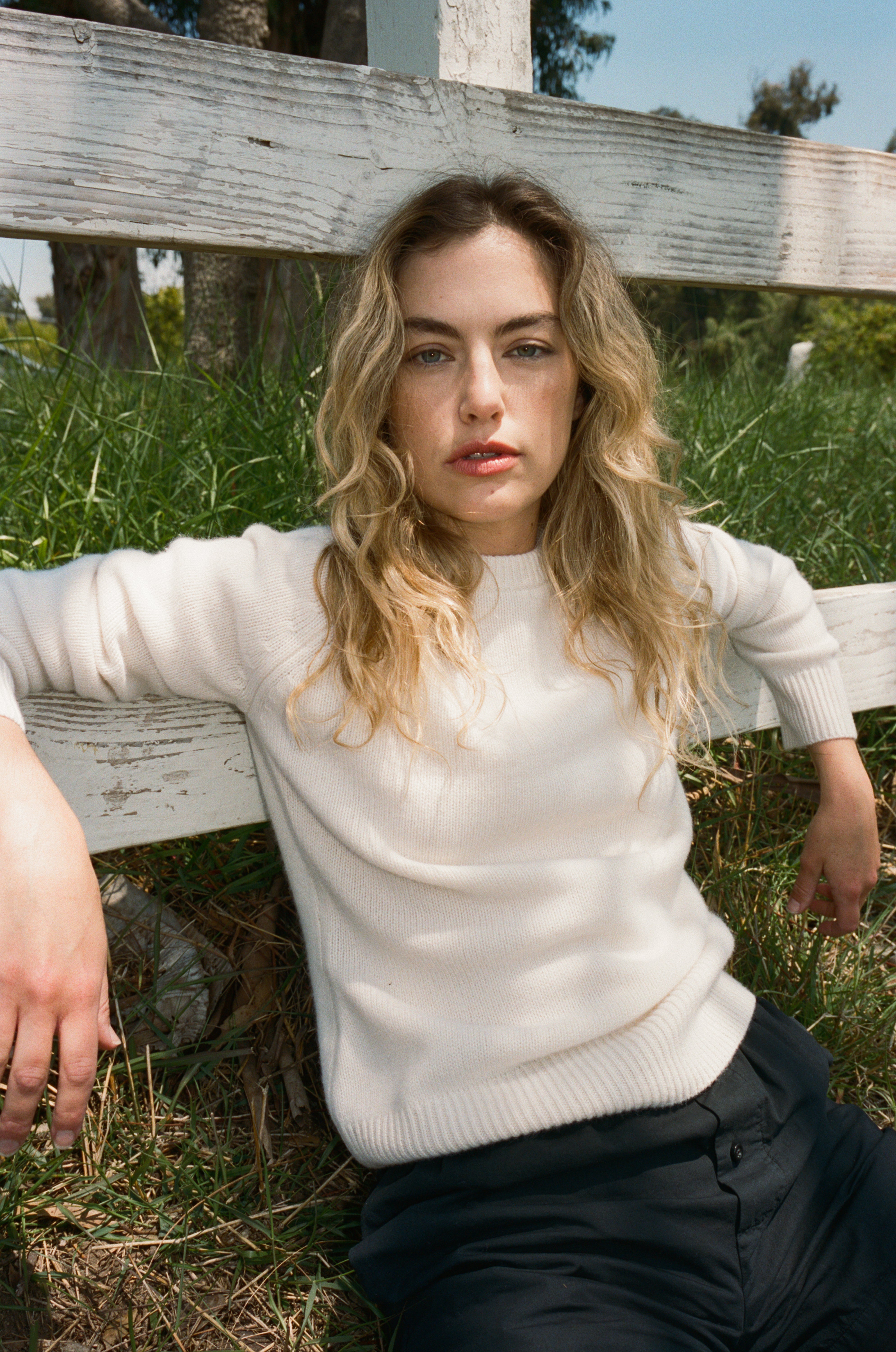 Female model wearing a white ultra-soft luxurious cashmere pullover sweater featuring a classic silhouette and raglan sleeves paired with black cotton poplin shorts - VIR VITA
#color_bone