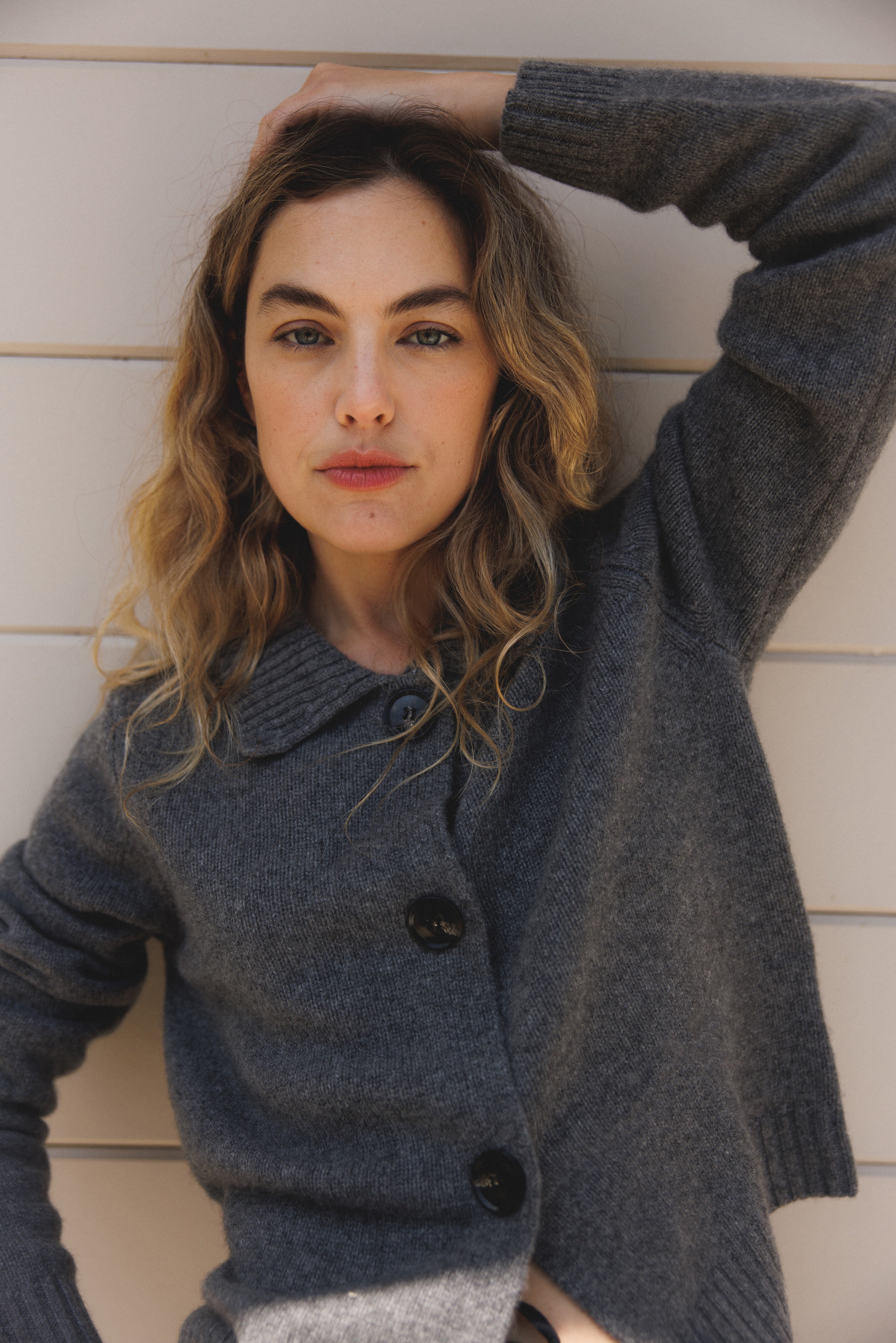 Female model wearing a grey ultra-soft luxurious cashmere cardigan featuring a classic silhouette with a collar and large buttons - VIR VITA
#color_stone grey