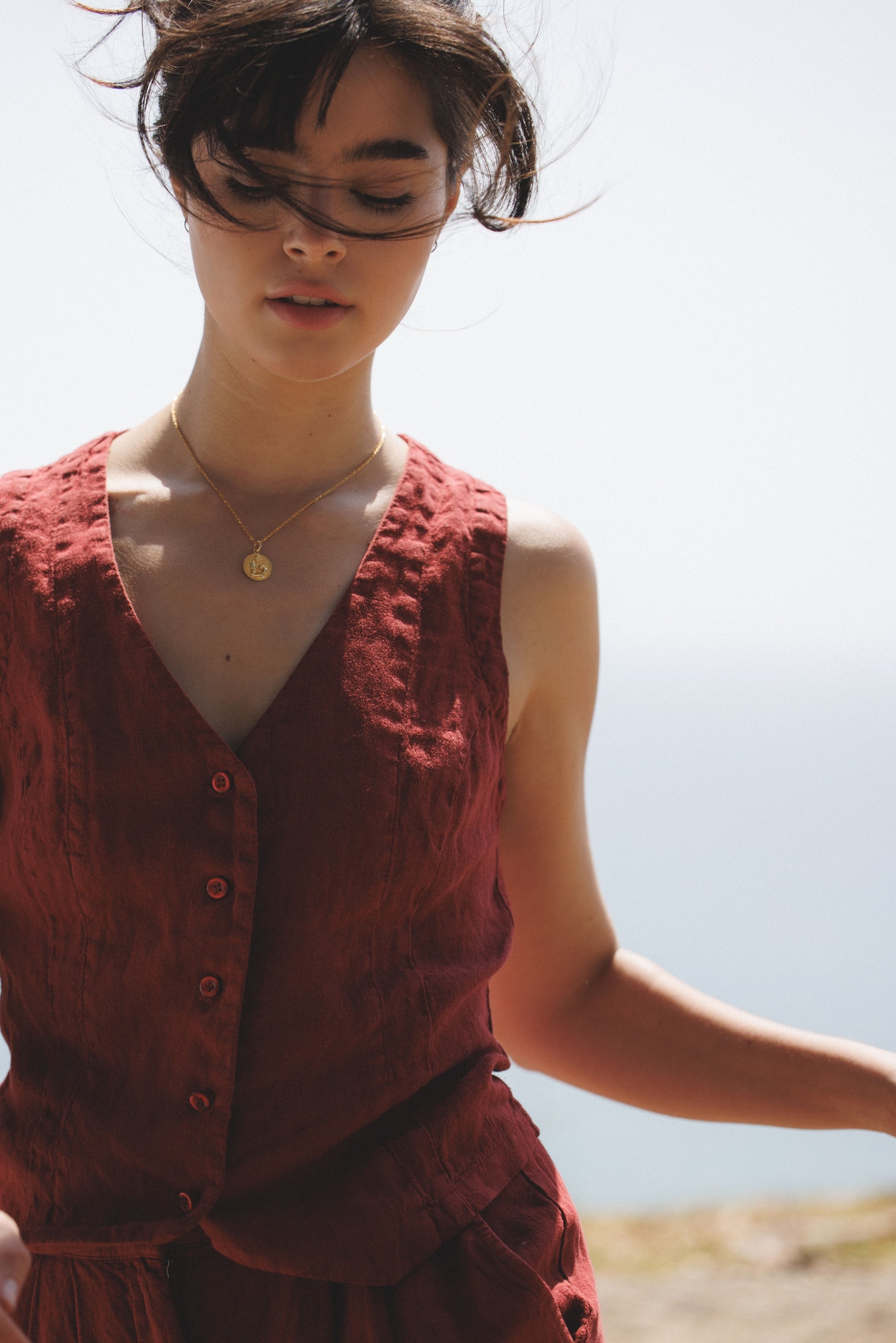 Female model, wearing a dark red colored sustainable 100% linen vest with matching Italian handcrafted buttons paired with red linen trousers- VIR VITA
#color_sun dried tomato