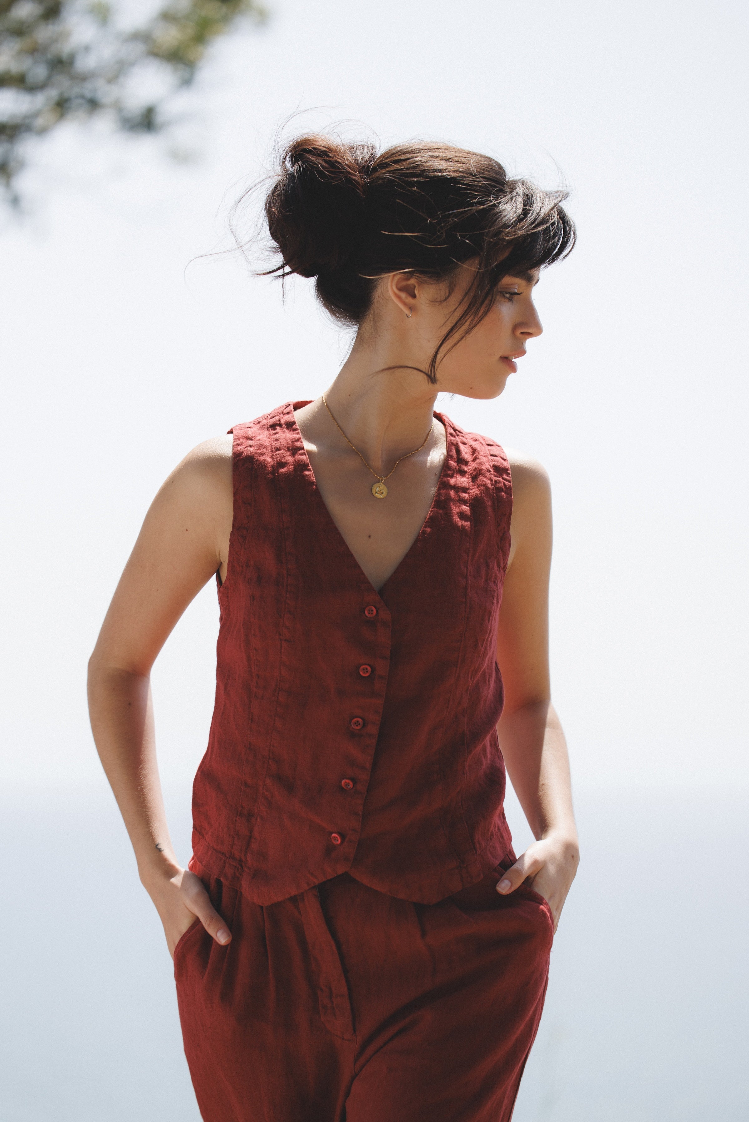 Female model, wearing a dark red colored sustainable 100% linen vest with matching Italian handcrafted buttons paired with dark red linen trousers- VIR VITA
#color_sun dried tomato