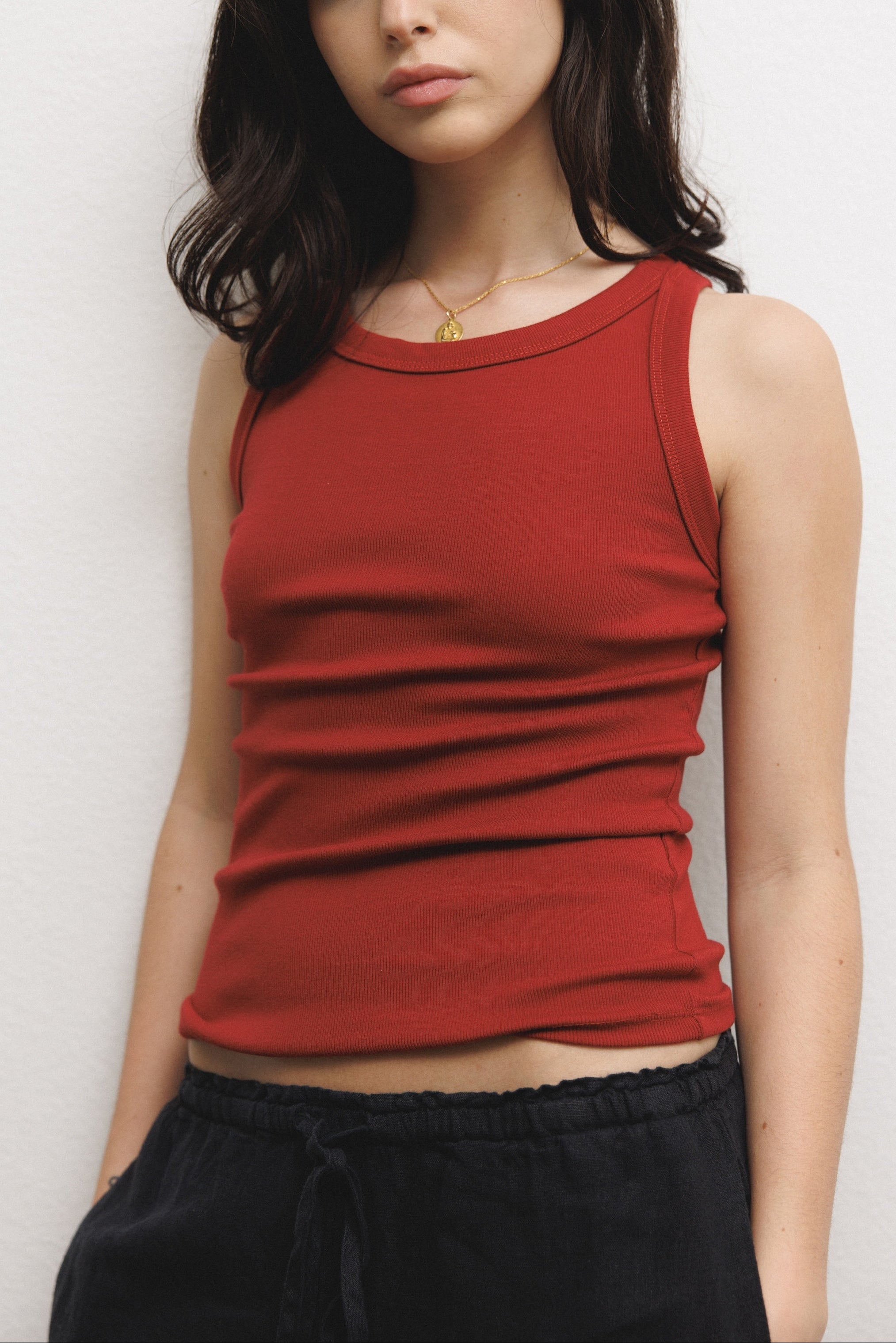 Female model wearing a supima cotton tank top featuring a racerback design in dark red paired with 100% linen drawstring pants in black - VIR VITA
#color_sun dried tomato