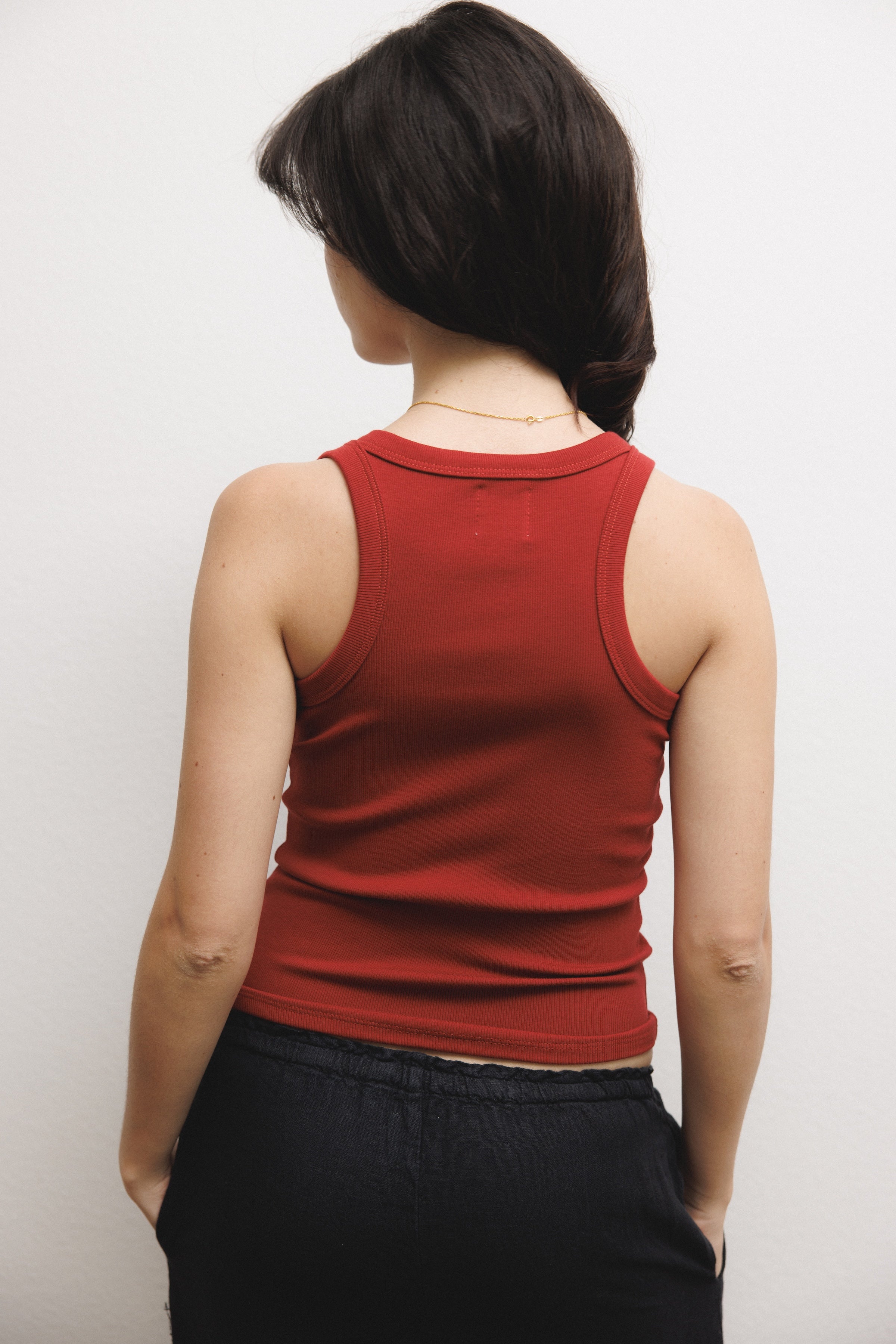 Female model wearing a supima cotton tank top featuring a racerback design in dark red paired with 100% linen drawstring pants in black - VIR VITA
#color_sun dried tomato