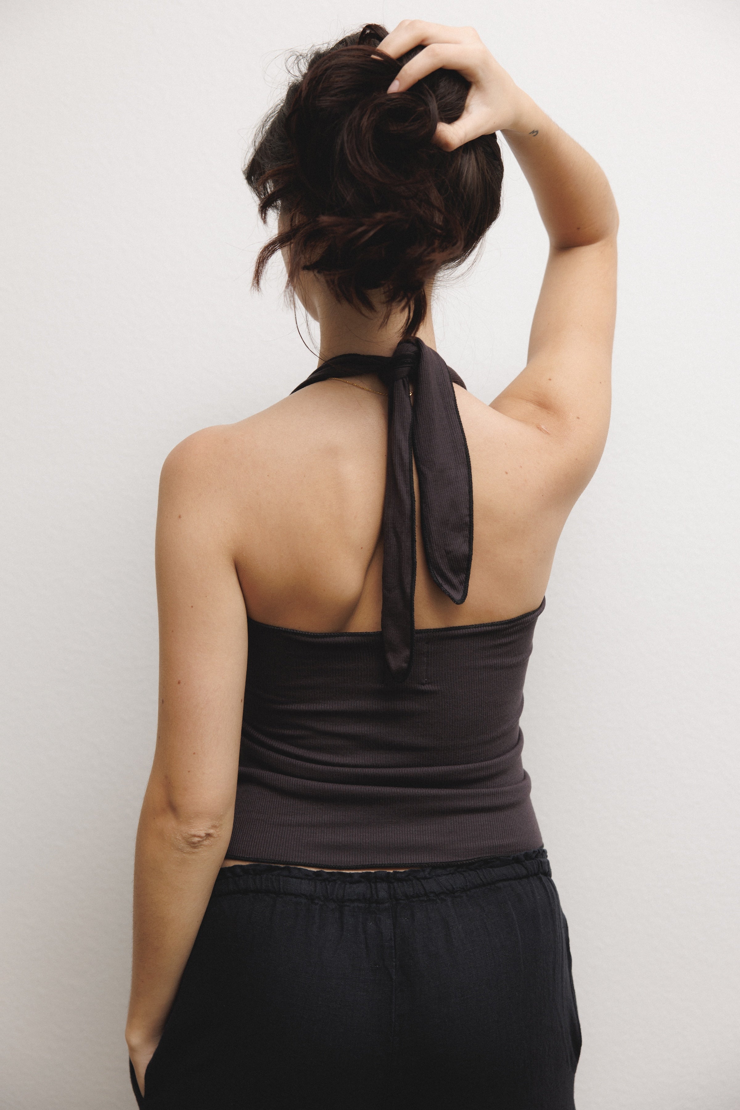 Female model wearing a soft and luxurious modal halter top in black paired with a 100% linen drawstring pant in black- VIR VITA
#color_black