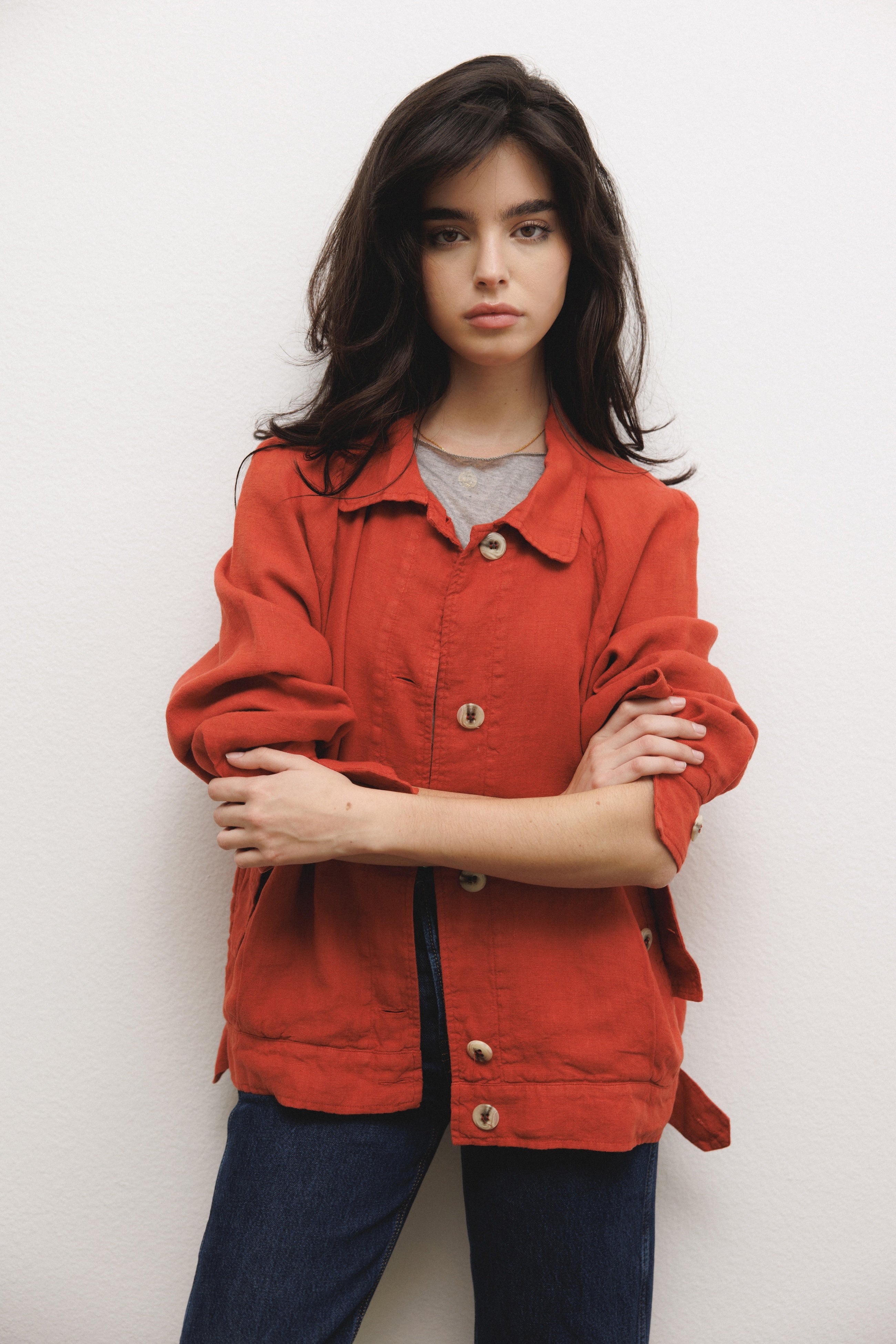 Female model wearing sustainable red 100% linen barn jacket with grey modal silk top and blue jeans - VIR VITA
#color_apple red