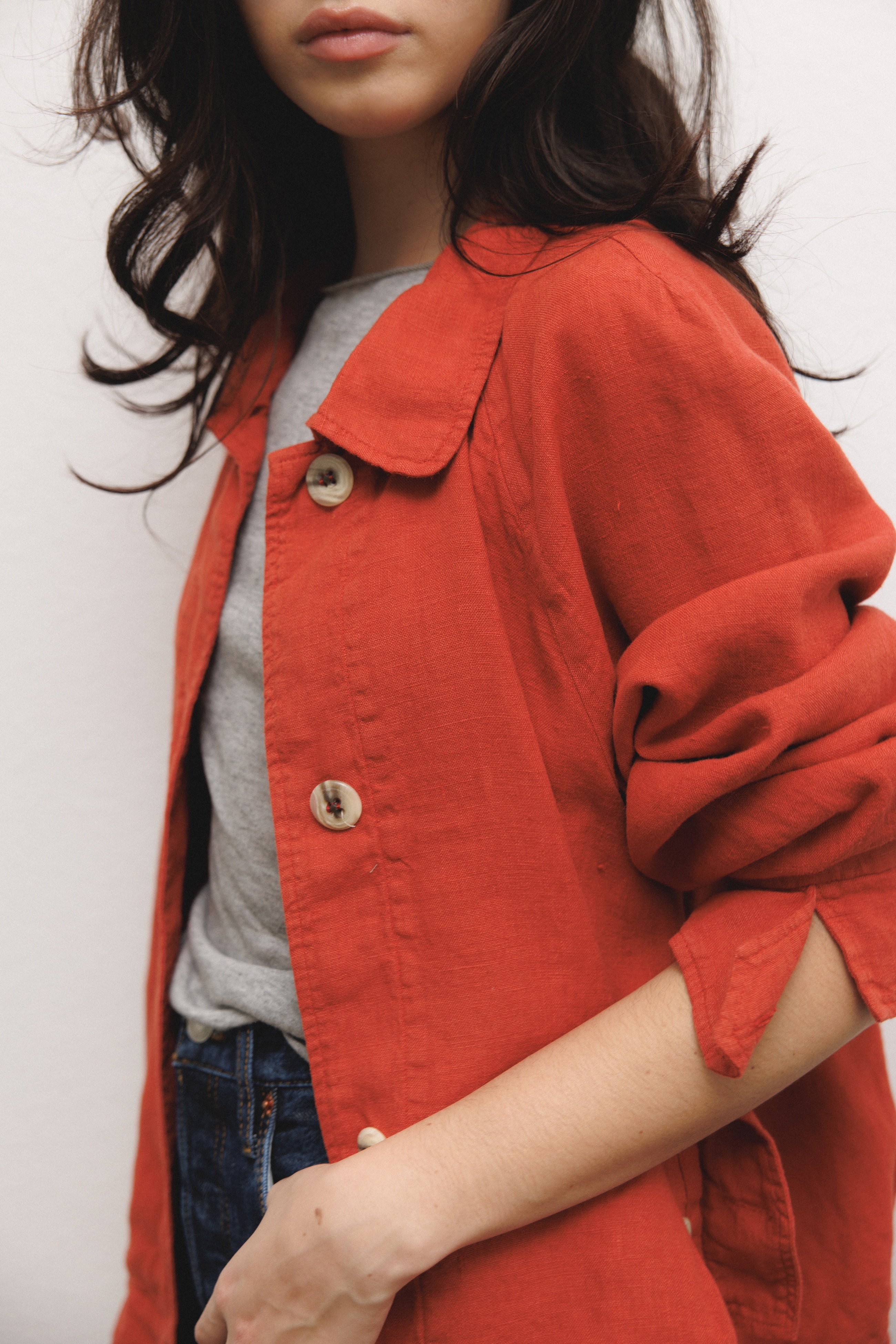 Female model wearing sustainable red 100% linen barn jacket with grey modal silk top and blue jeans - VIR VITA
#color_apple red