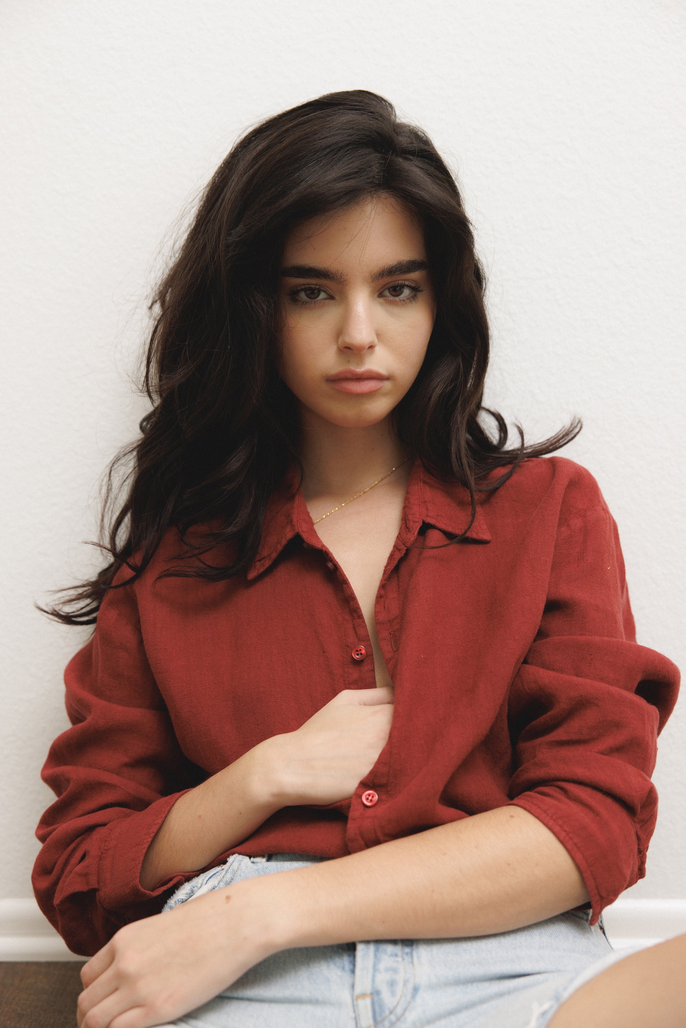 Female model, wearing a dark red colored sustainable oversized 100% linen button down long sleeve paired with blue denim shorts - VIR VITA
#color_sun dried tomato