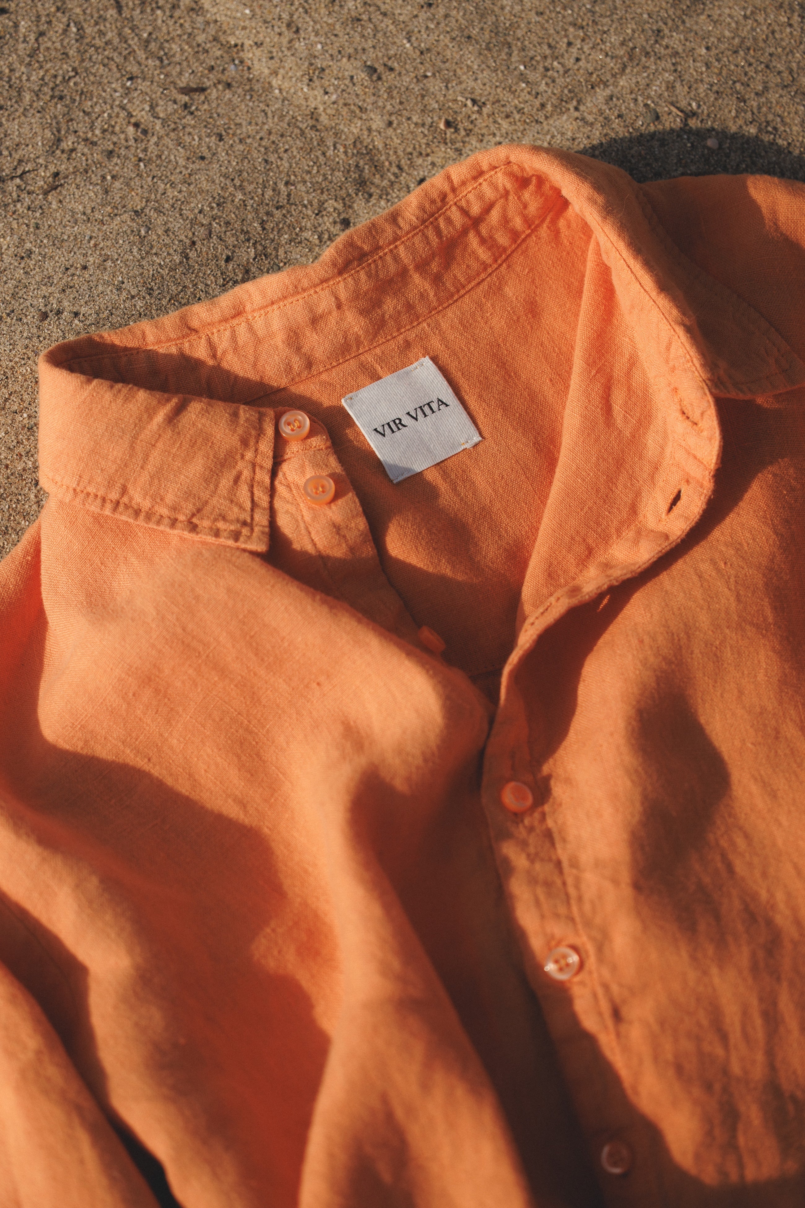 Orange colored sustainable oversized 100% linen button down long sleeve laid out in sand- VIR VITA #color_melon