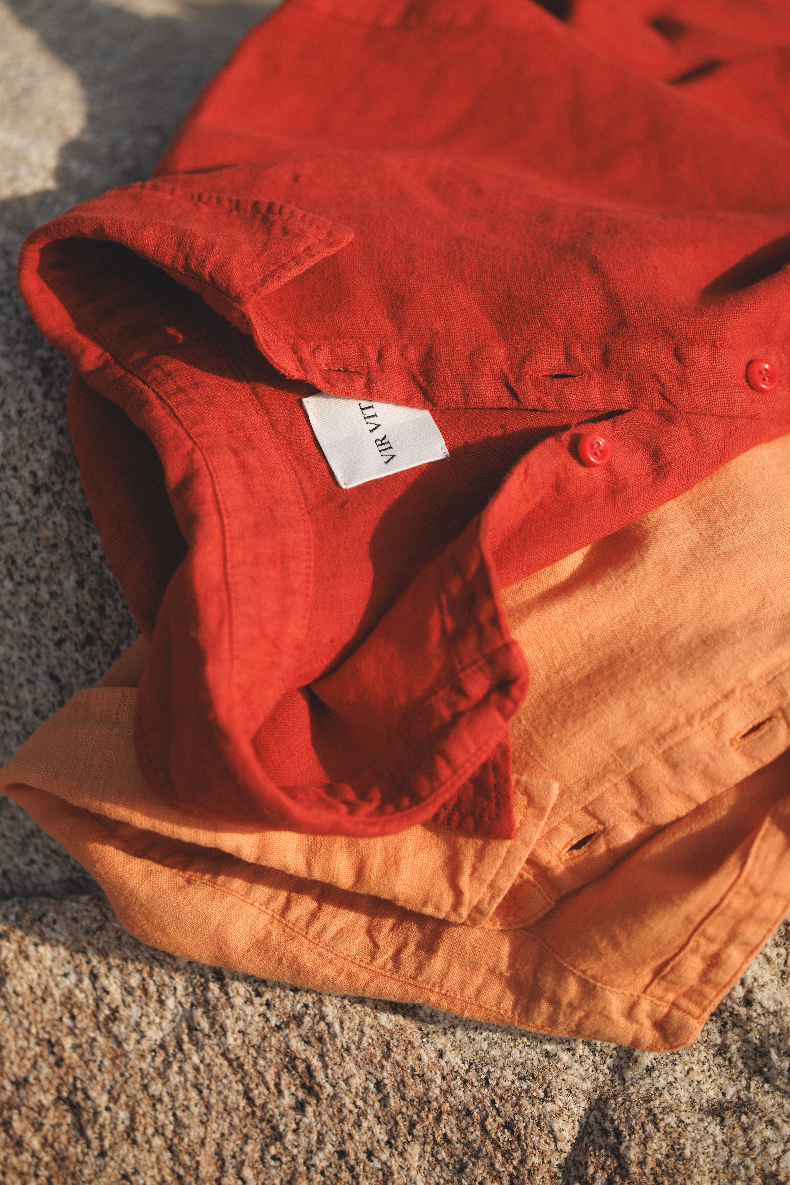 Red sustainable oversized 100% linen button down long sleeve laid out in sand on top of orange oversized 100% linen button down long sleeve - VIR VITA
#color_apple red