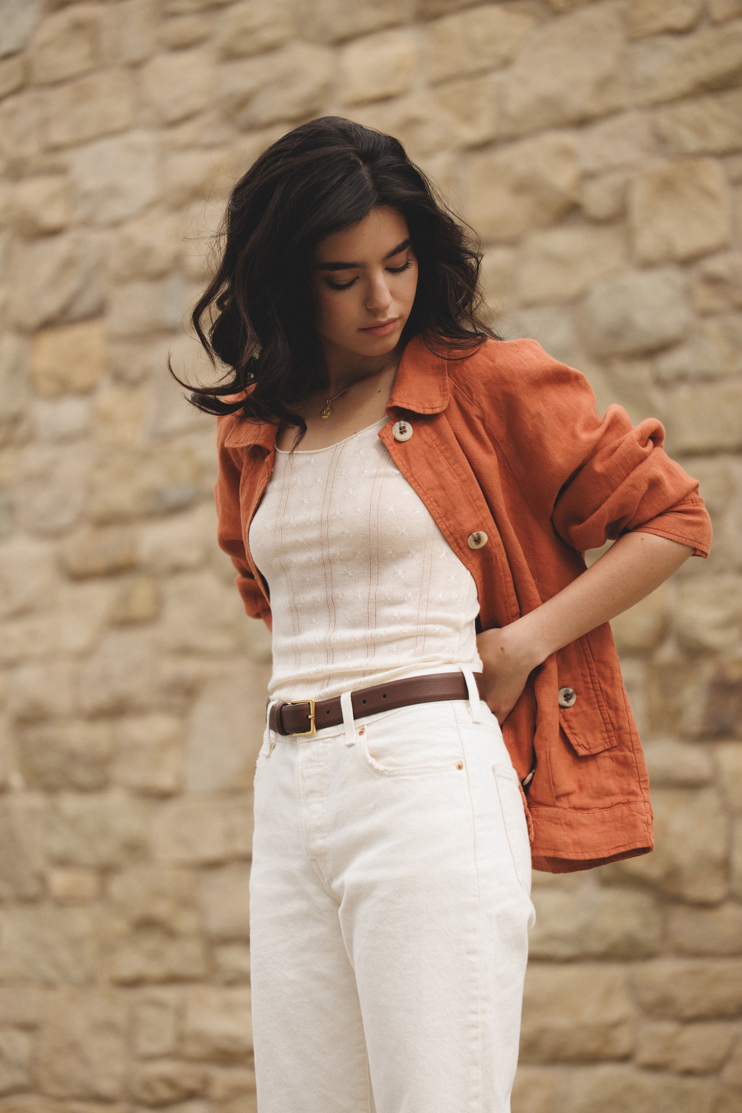 Female model wearing sustainable terracotta 100% linen barn jacket with white jeans, a brown belt, and a white cashmere top - VIR VITA
#color_sedona