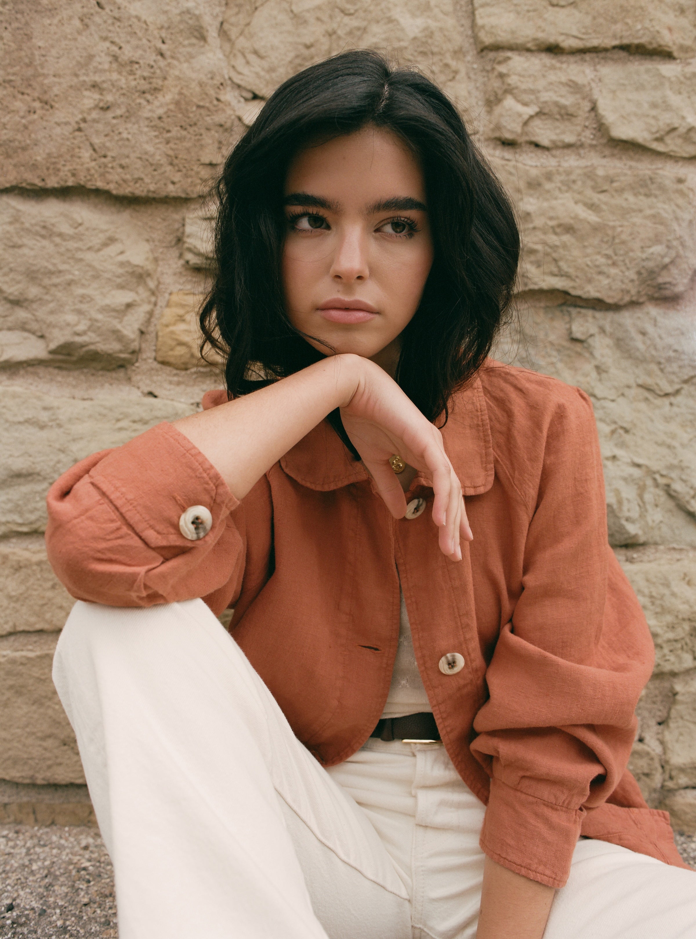 Female model wearing sustainable terracotta 100% linen barn jacket with white jeans, a brown belt, and a white cashmere top - VIR VITA
#color_sedona