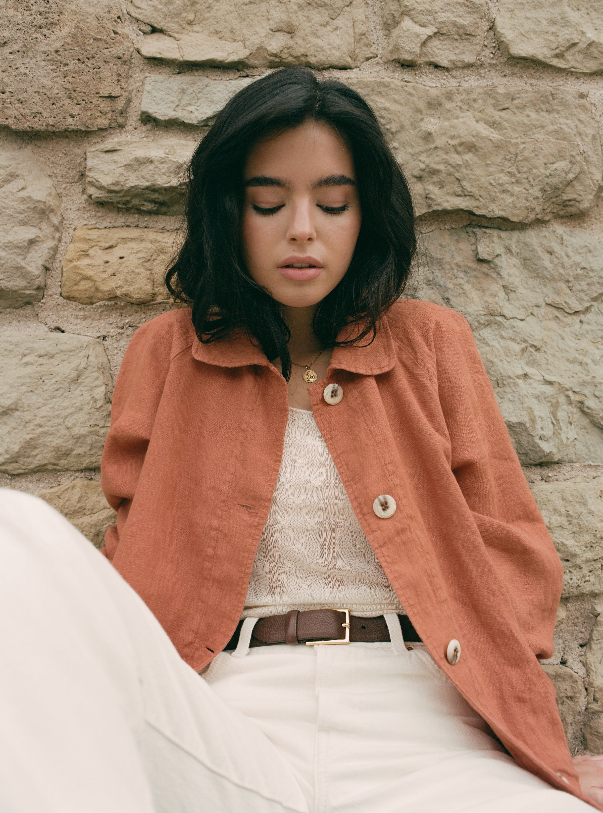 Female model wearing sustainable terracotta 100% linen barn jacket with white jeans, a brown belt, and a white cashmere top - VIR VITA
#color_sedona