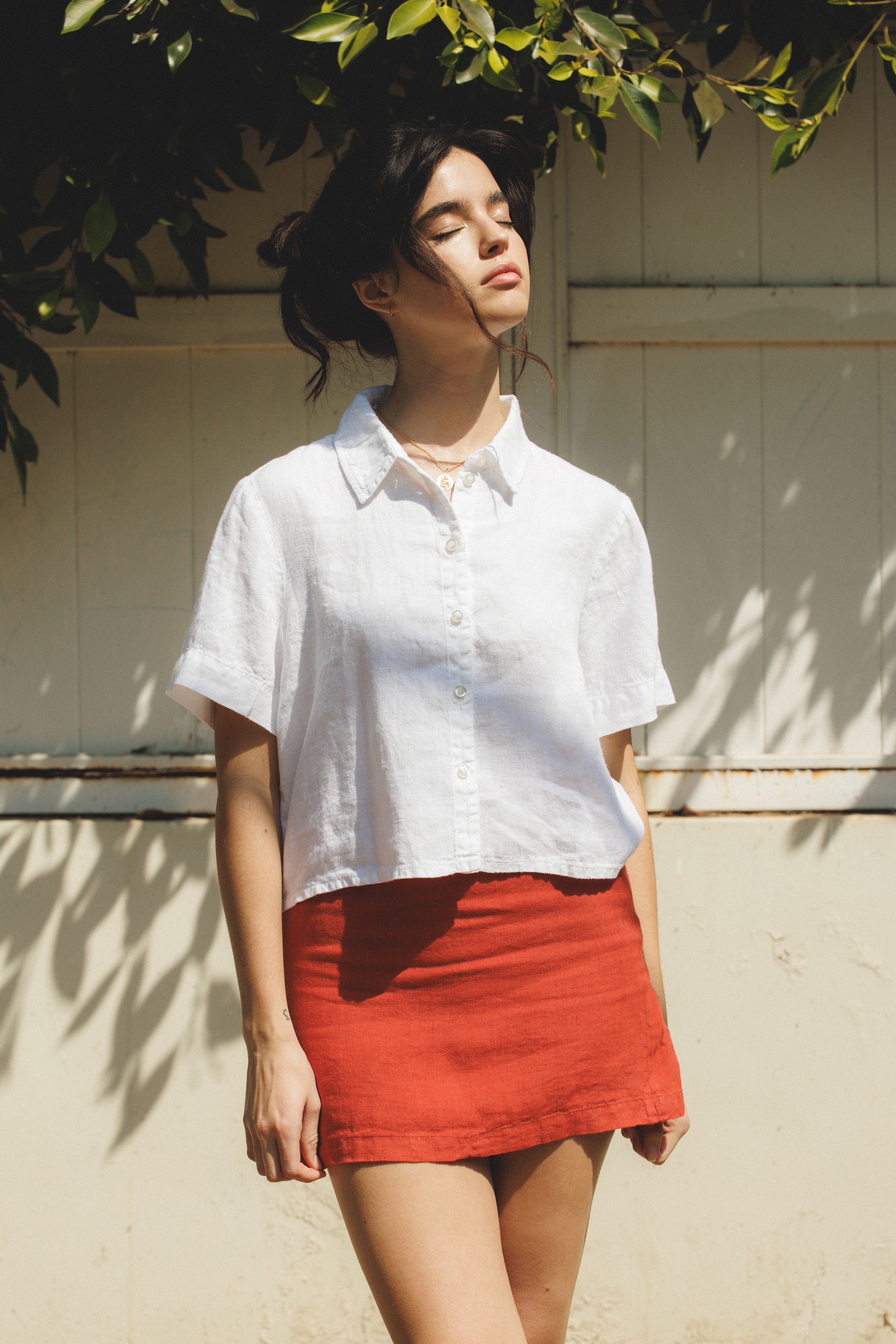 Female model wearing sustainable white short sleeve button up 100% linen shirt and matching linen mini skirt in red - VIR VITA
#color_white