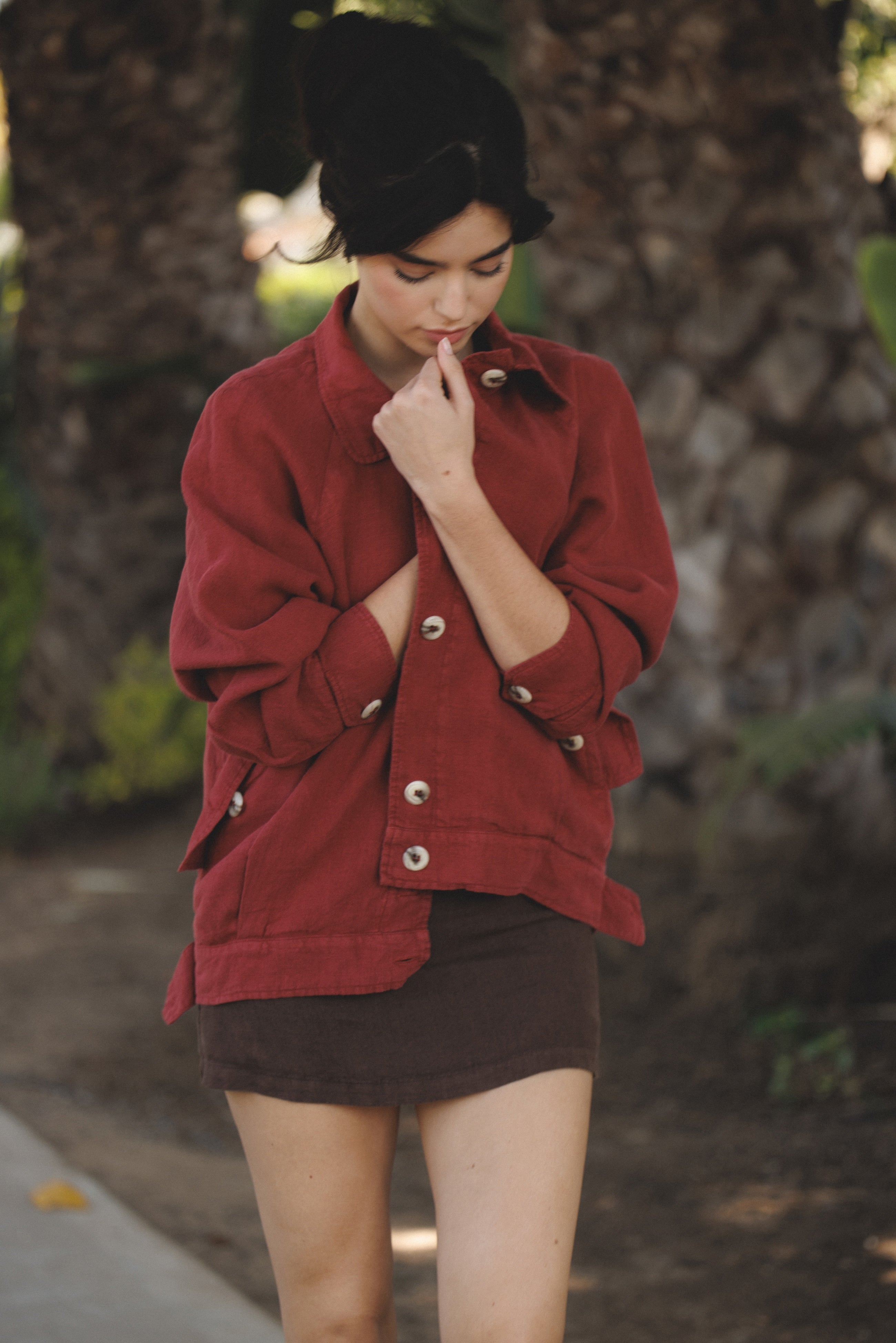 Female model wearing sustainable burgundy red 100% linen barn jacket with brown linen mini skirt - VIR VITA
#color_sun dried tomato