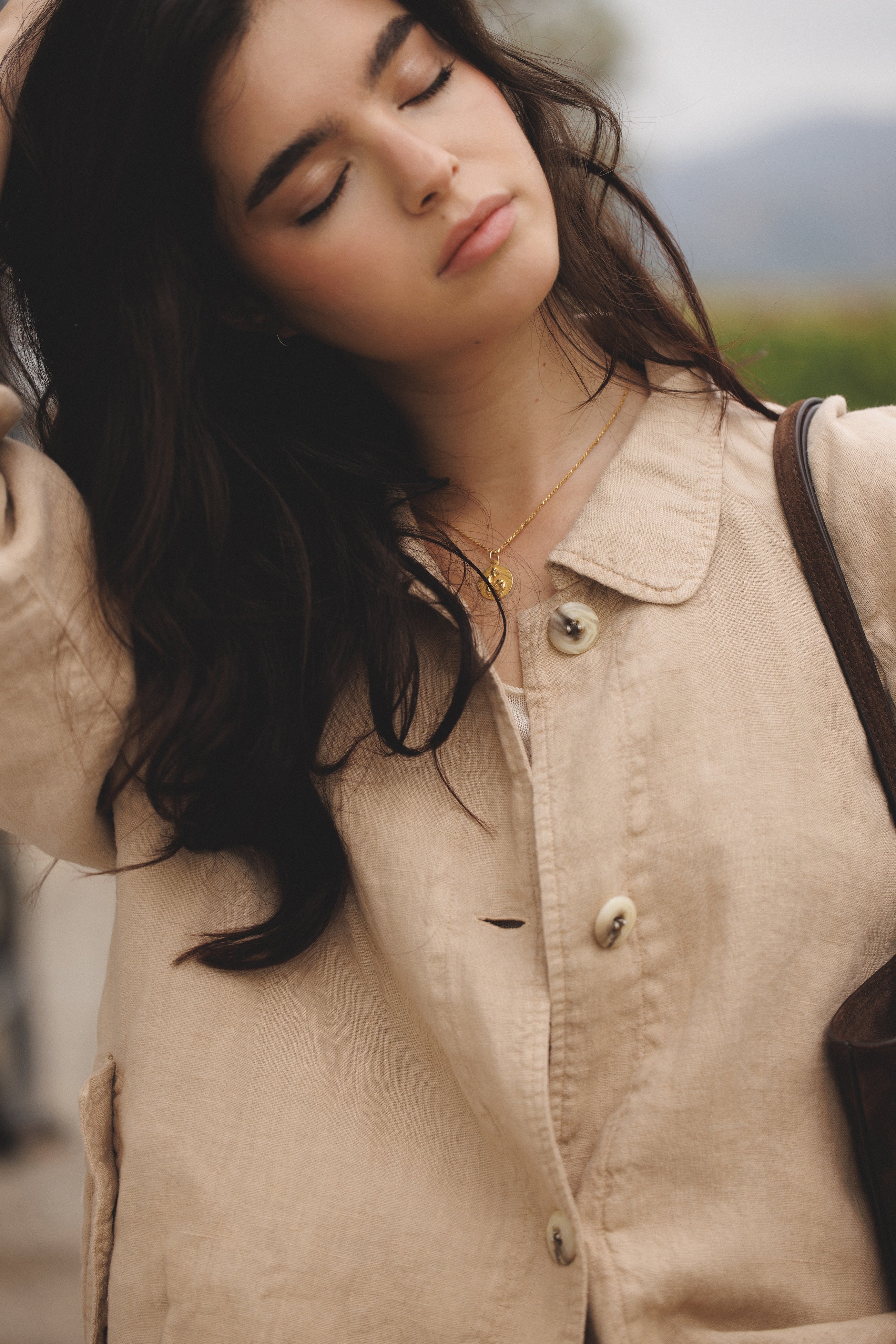 Female model wearing sustainable toffee beige 100% linen barn jacket holding a brown suede bag - VIR VITA
#color_toffee