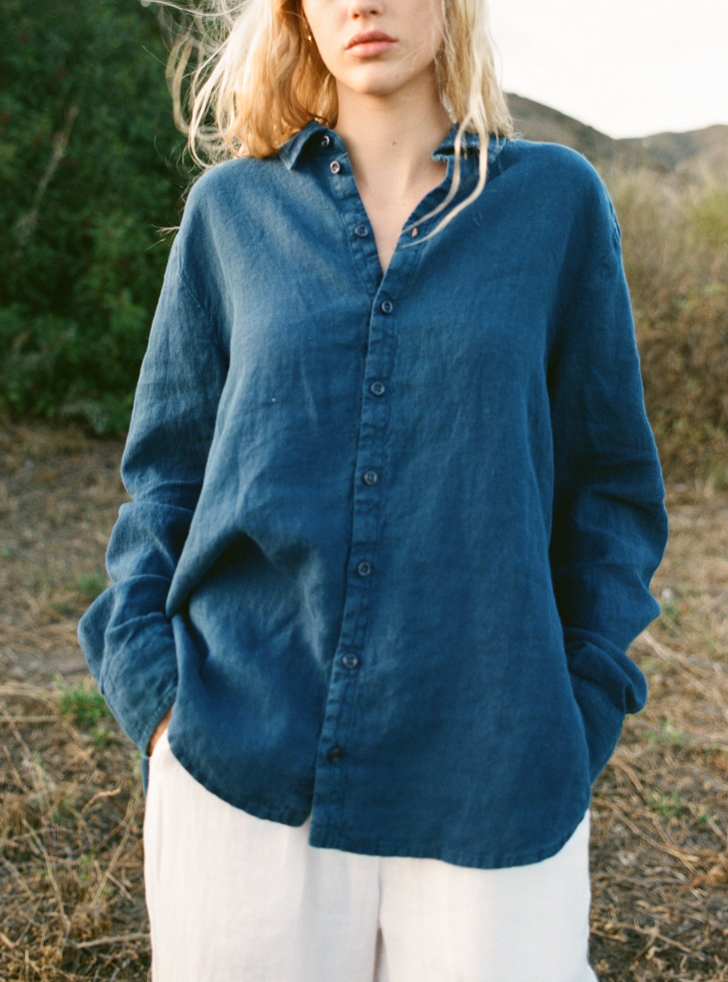 Female model wearing a navy blue sustainable oversized 100% linen button down long sleeve paired with white linen pants- VIR VITA
#color_navy