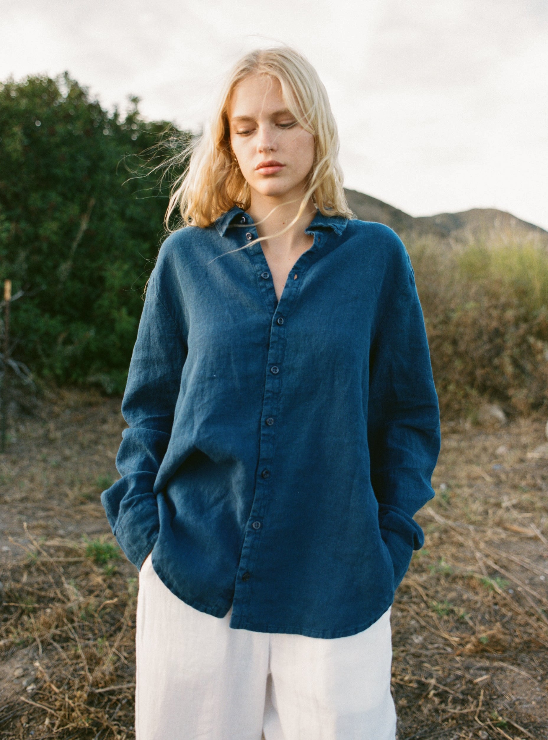 Female model wearing a navy blue sustainable oversized 100% linen button down long sleeve paired with white linen pants - VIR VITA
#color_navy