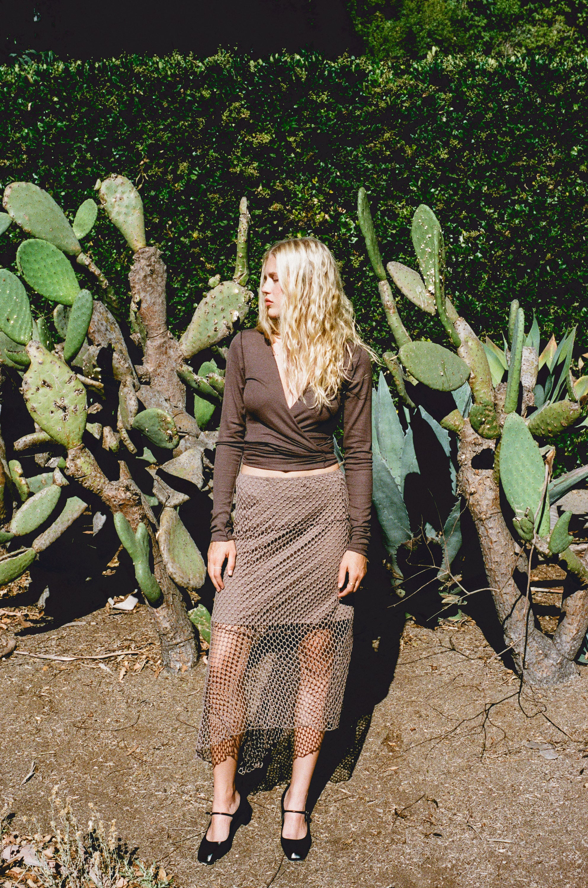 Female model wearing an exquisite crochet skirt featuring an asymmetrical silhouette in light brown paired with a modal knit long sleeve wrap top in dark brown - VIR VITA
#color_bark
