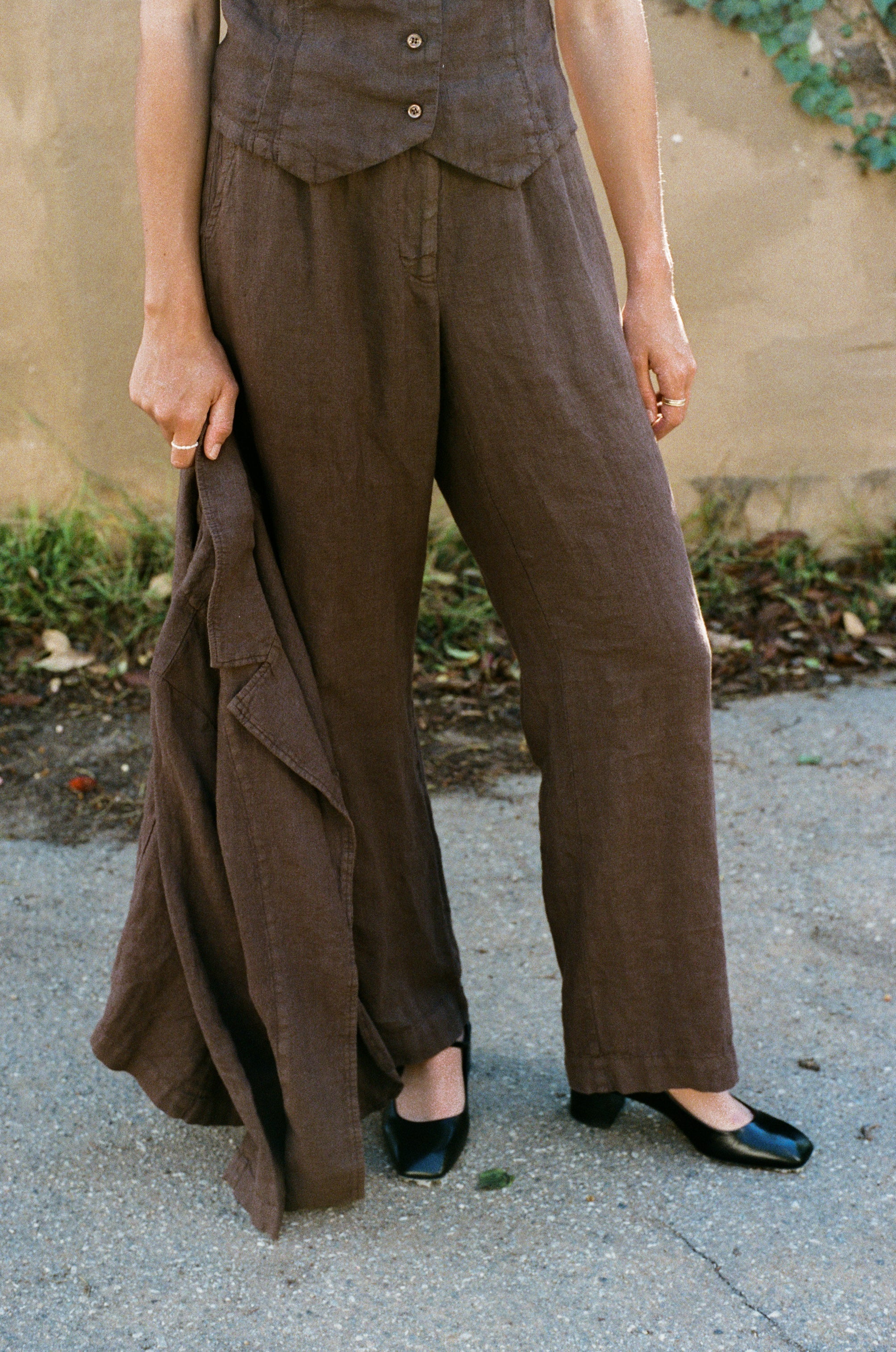 Female model wearing a 100% linen trouser featuring a high waisted double pleat silhouette in dark brown paired with a matching 100% linen blazer in dark brown and a 100% linen vest in dark brown- VIR VITA
#color_chestnut
