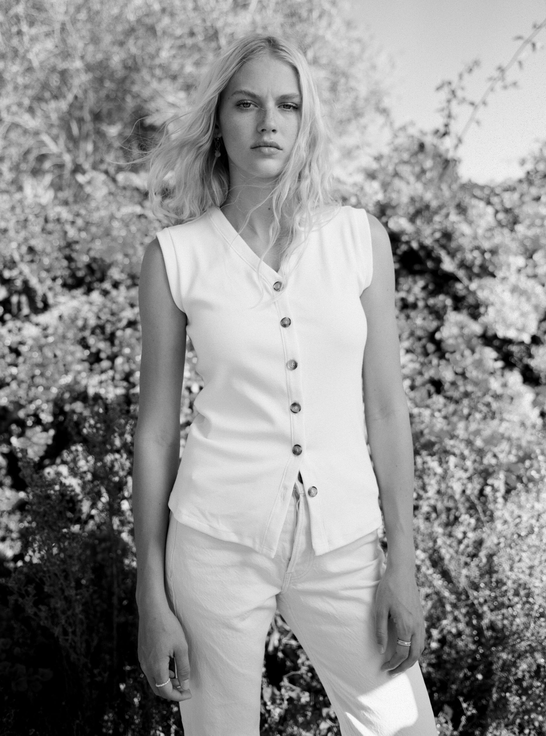 Female model wearing a sustainable supima cotton white ribbed vest with italian buttons paired with white jeans. Classic, timeless, elegant, french style. Natural organic clothing - VIR VITA
#color_white