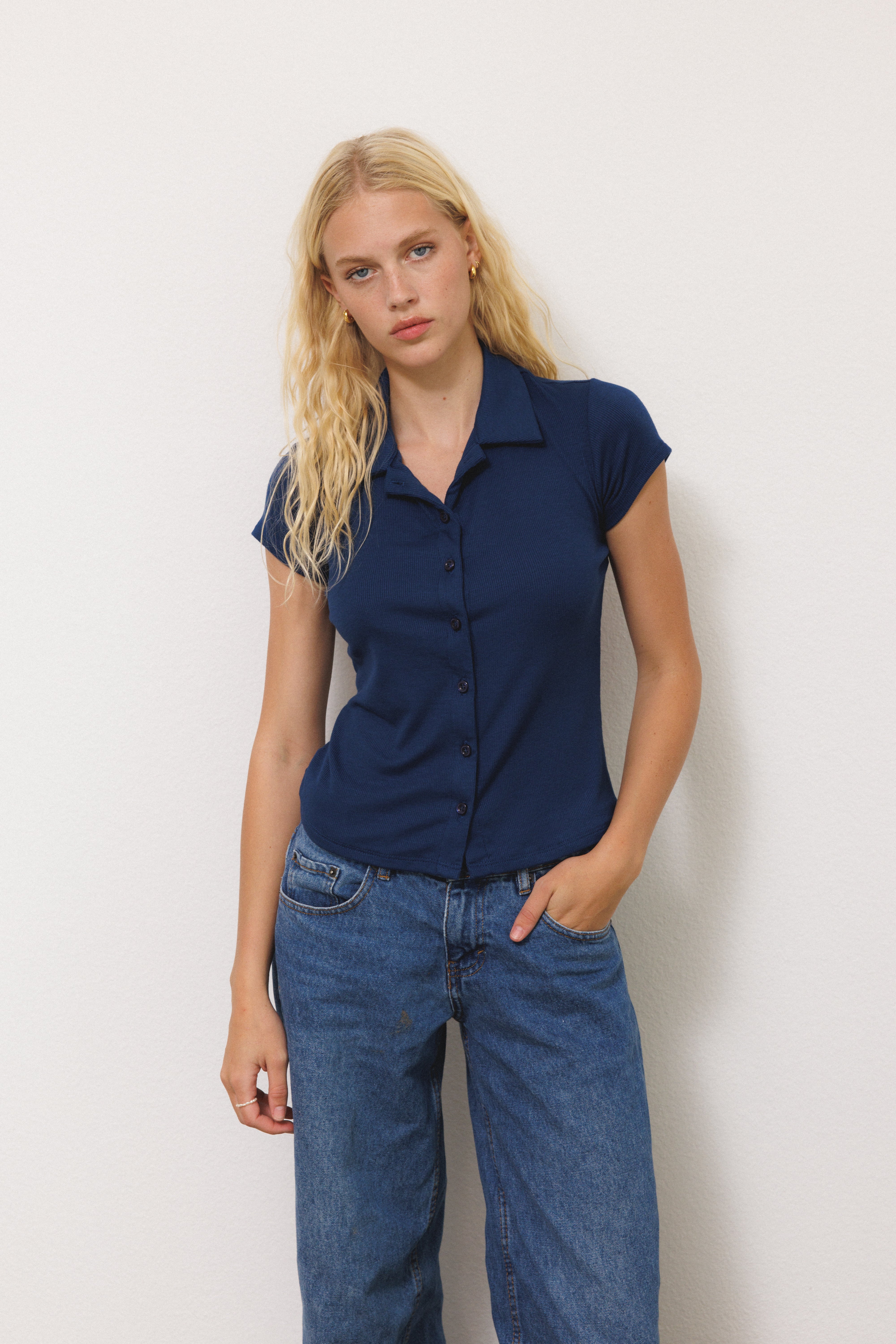 Female model wearing navy blue sustainable micro modal short sleeve ribbed polo top with italian button detailing paired with blue jeans. Classic, timeless, elegant, french style. Natural organic clothing - VIR VITA
#color_navy