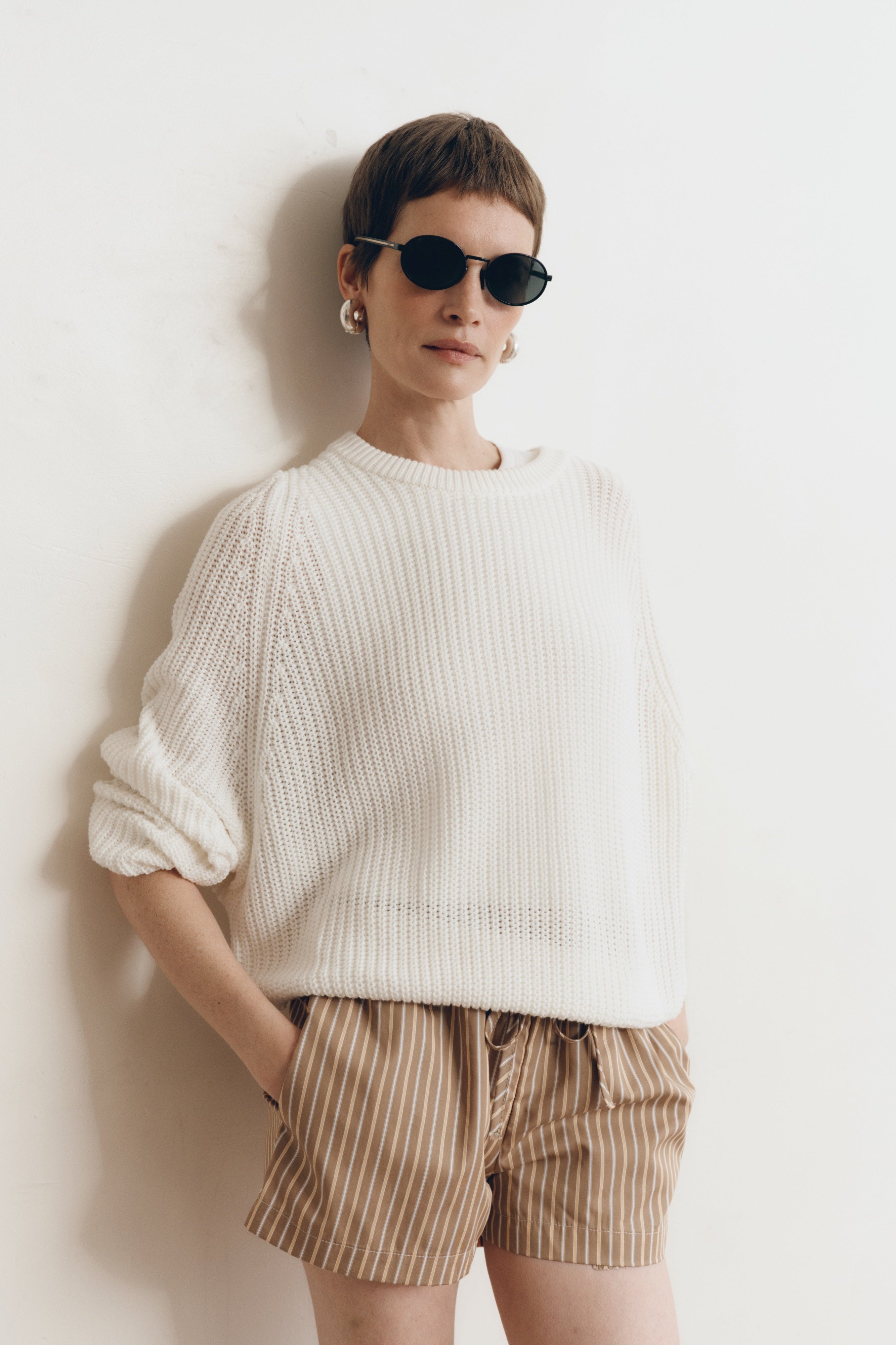 Posed female model wearing brown 100% cotton sustainable drawstring relaxed shorts paired with a cotton knit sweater in white and black sunglasses - VIR VITA
#color_canyon stripe