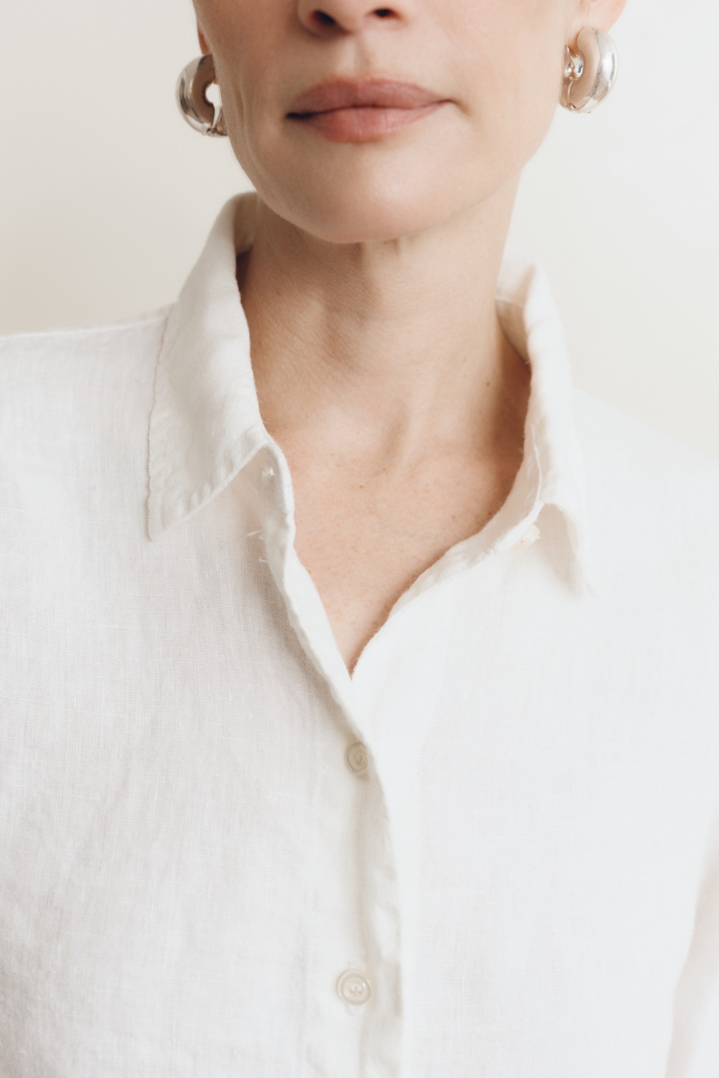 Posed female model wearing a sustainable 100% linen classic button up collared shirt in white - VIR VITA
#color_white