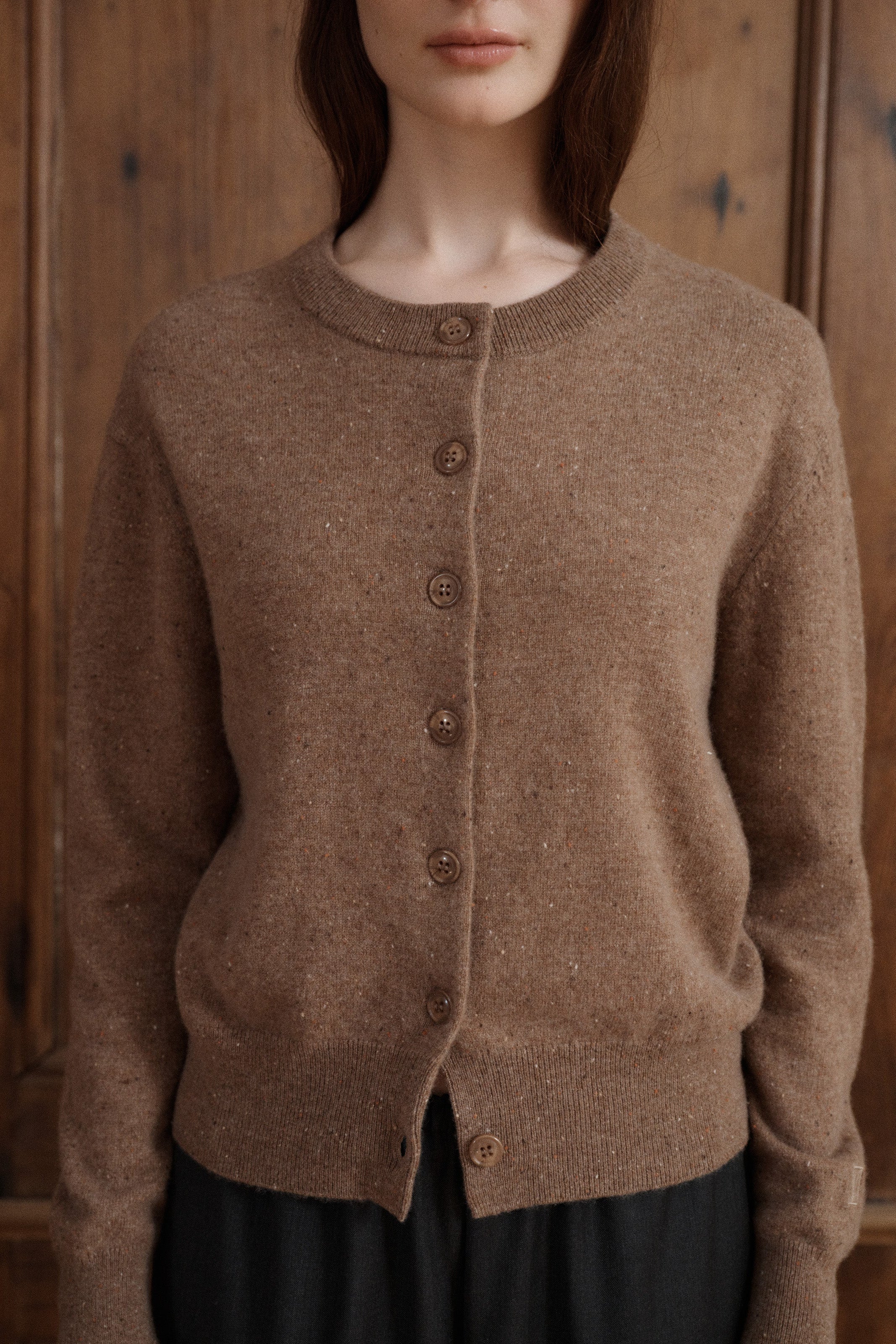 Female model posing in a speckled light brown cardigan made in soft cashmere with slouchy details to create a relaxed silhouette. Paired with dark grey elastic waist wool trousers. - VIR VITA
#color_toastedwalnut