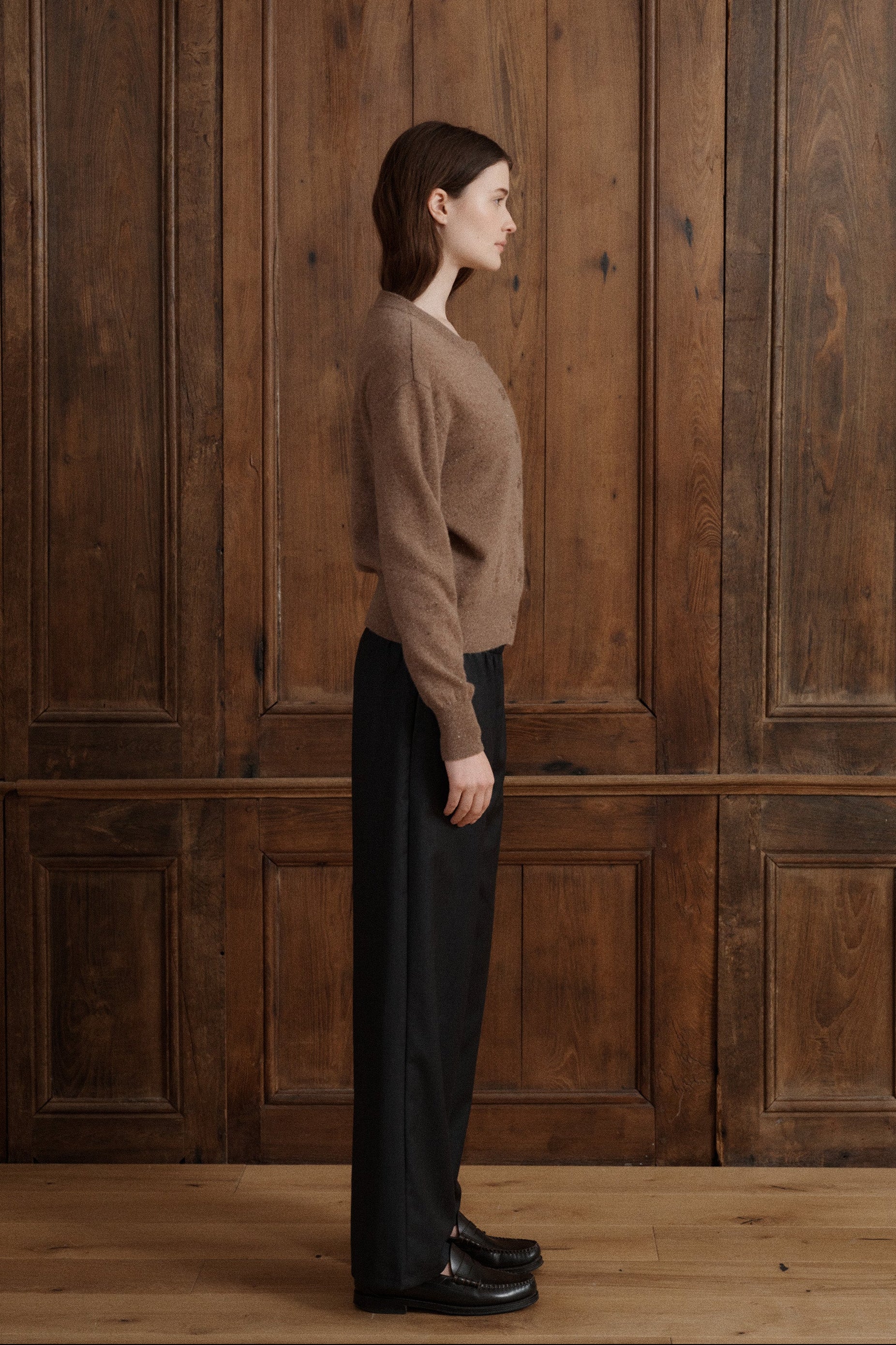 Female model posing in a speckled light brown cardigan made in soft cashmere with slouchy details to create a relaxed silhouette. Paired with dark grey elastic waist wool trousers and black loafers. - VIR VITA
#color_toastedwalnut