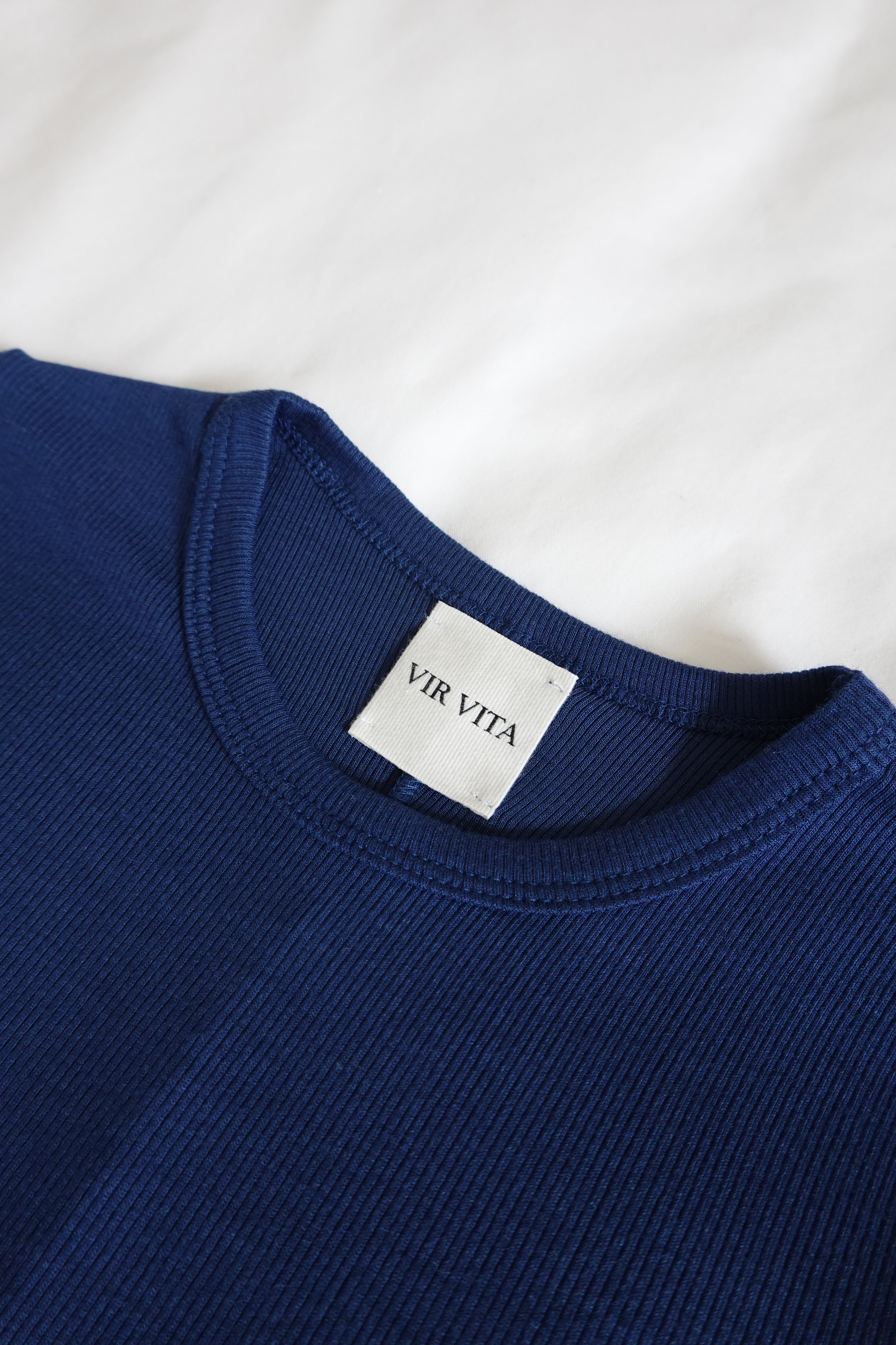 navy fitted tee laid flat on bed 
#color_navy