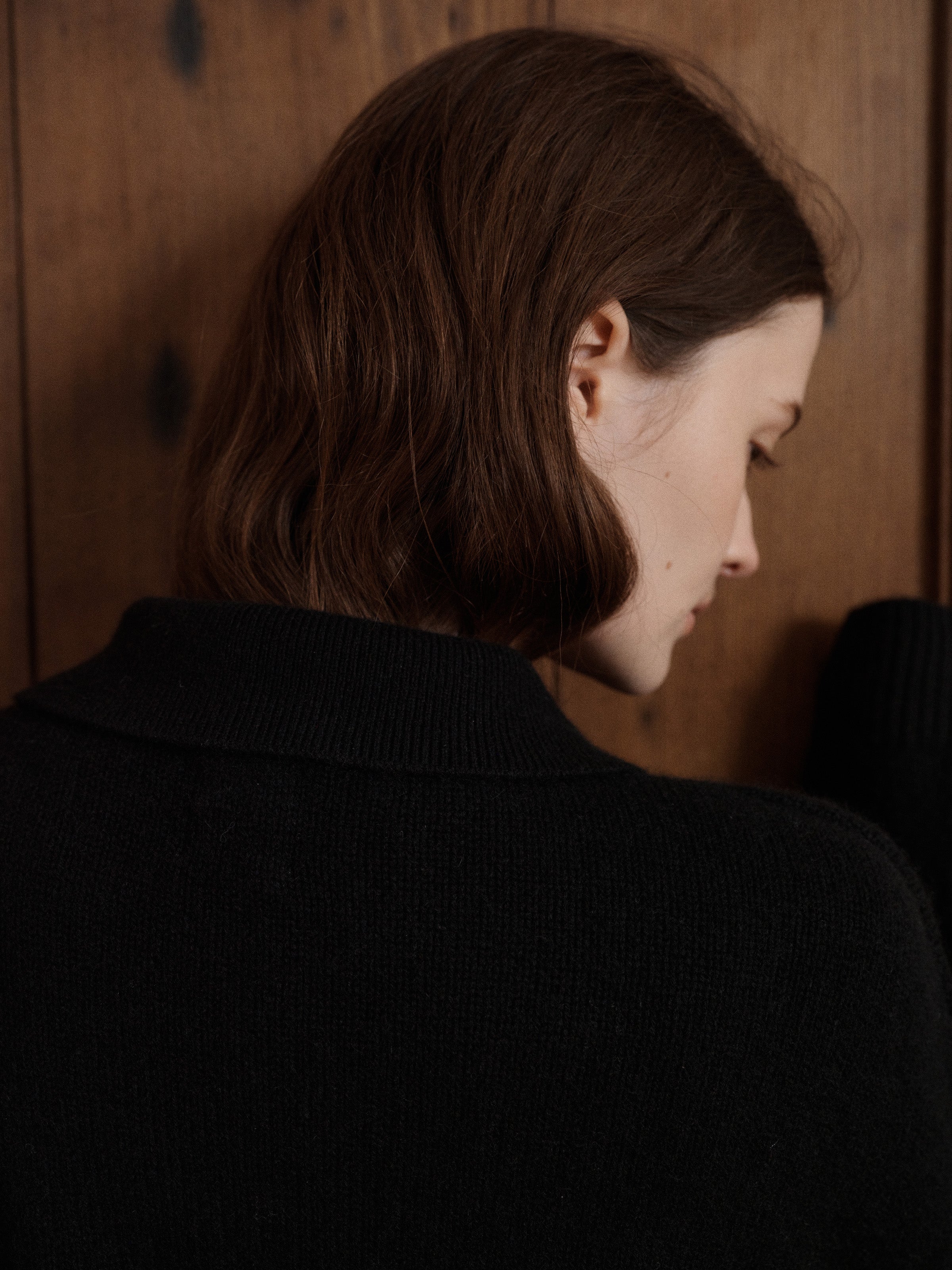 Female model posing wearing a black polo sweater crafted from soft cashmere. Designed with a structured collar, shoulder, and four-button front closure for a timeless look. - VIR VITA 
#color_black
