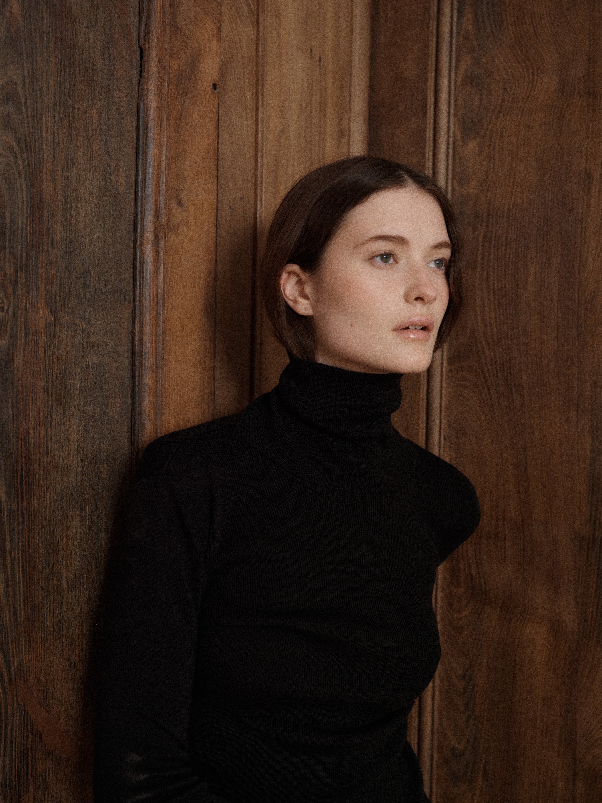 Female model posing wearing a black fitted turtleneck crafted from a fine wool, cashmere and silk blend.  - VIR VITA
#color_black