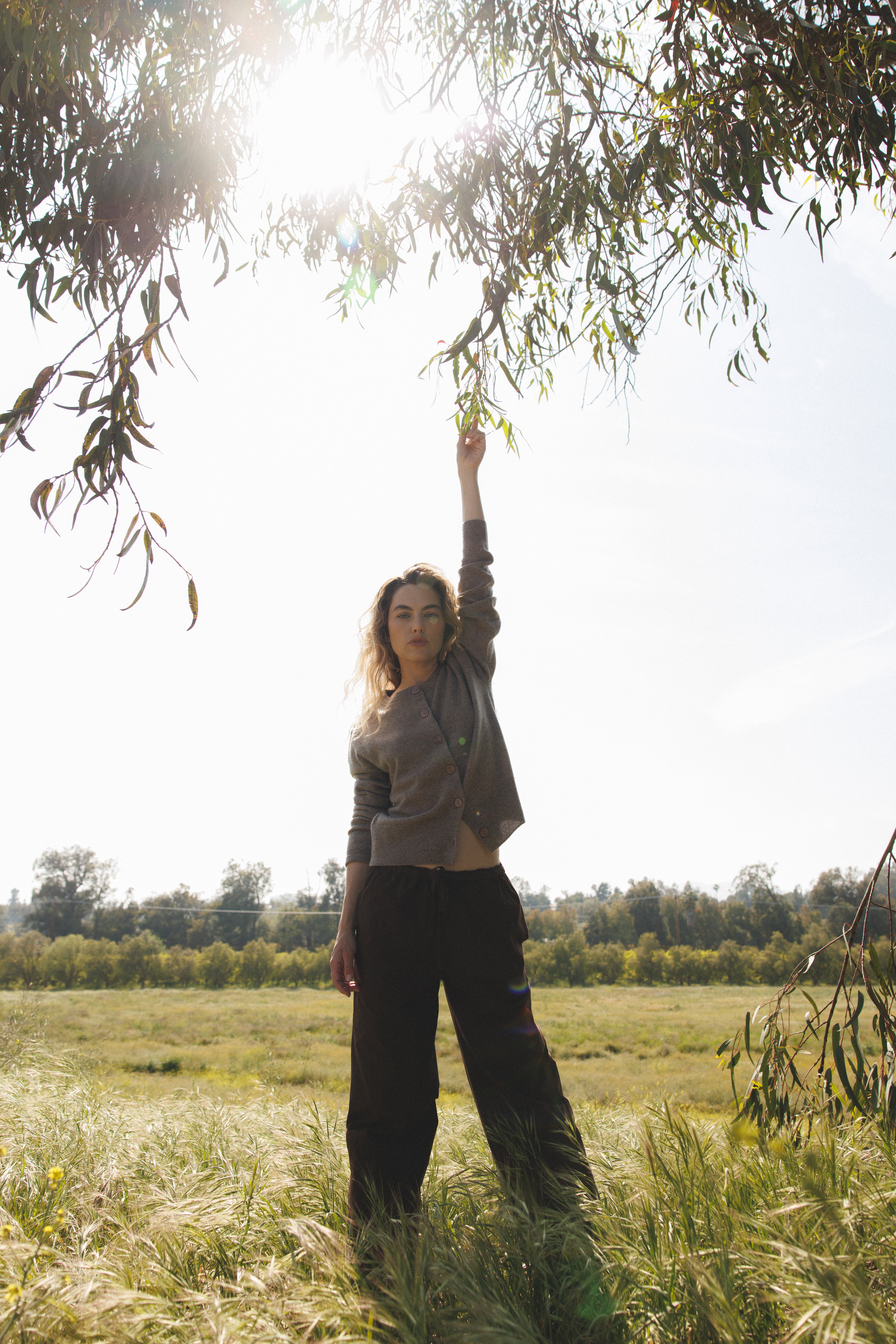 Female model standing in a field wearing a  light brown ultra-soft luxurious cashmere button up cardigan paired with dark brown drawstring pants - VIR VITA
#color_walnut