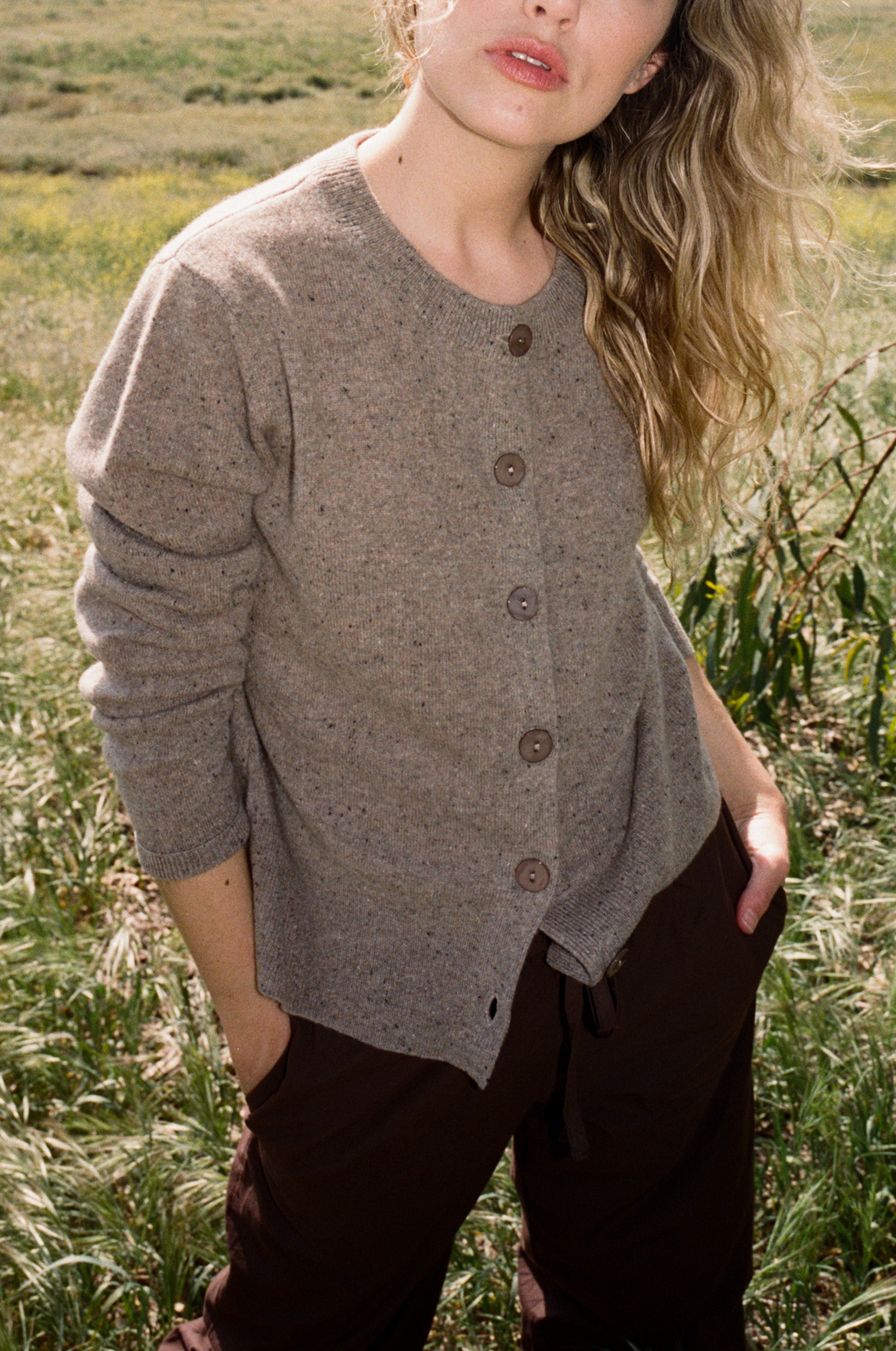 Female model standing in a field wearing a light brown ultra-soft luxurious cashmere button up cardigan paired with dark brown drawstring pants - VIR VITA
#color_walnut