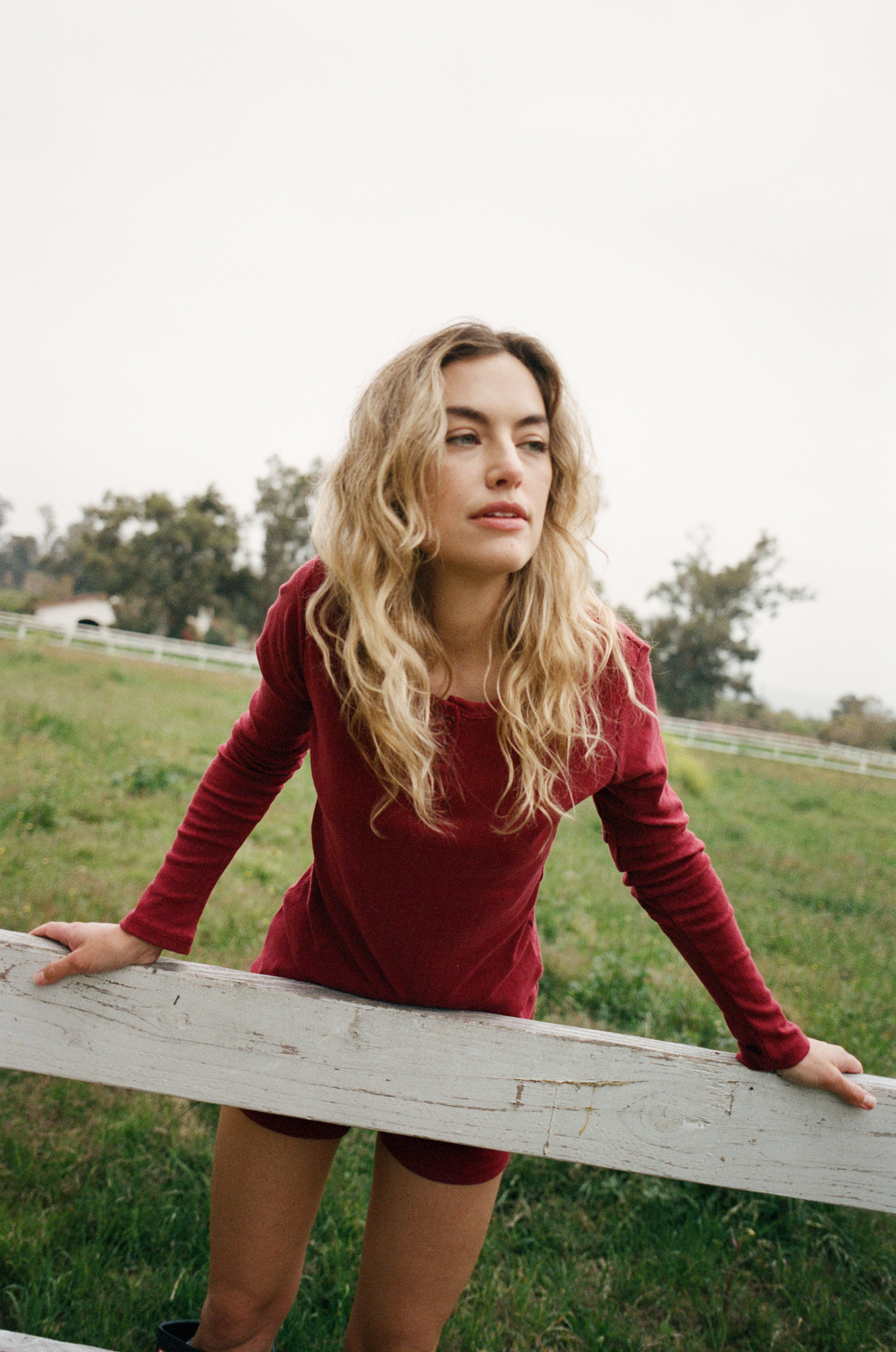 Female model leaning against a fence wearing a dark red cotton pointelle henley long sleeve top with matching buttons paired with cotton pointelle lounge shorts in dark red - VIR VITA
#color_sun dried tomato
