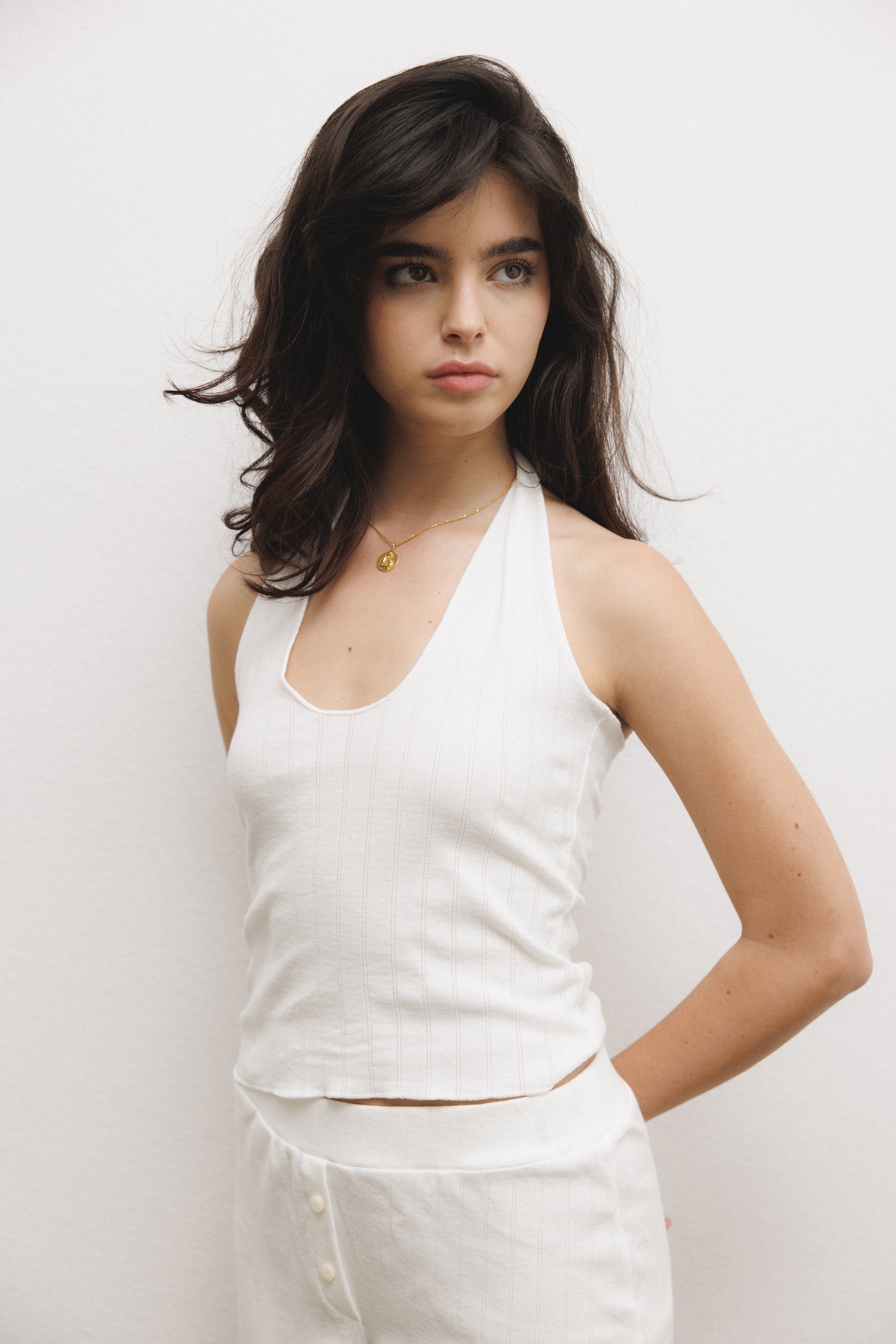 Female model wearing white pointelle halter top made of 100% recycled cotton - VIR VITA
#color_coconut