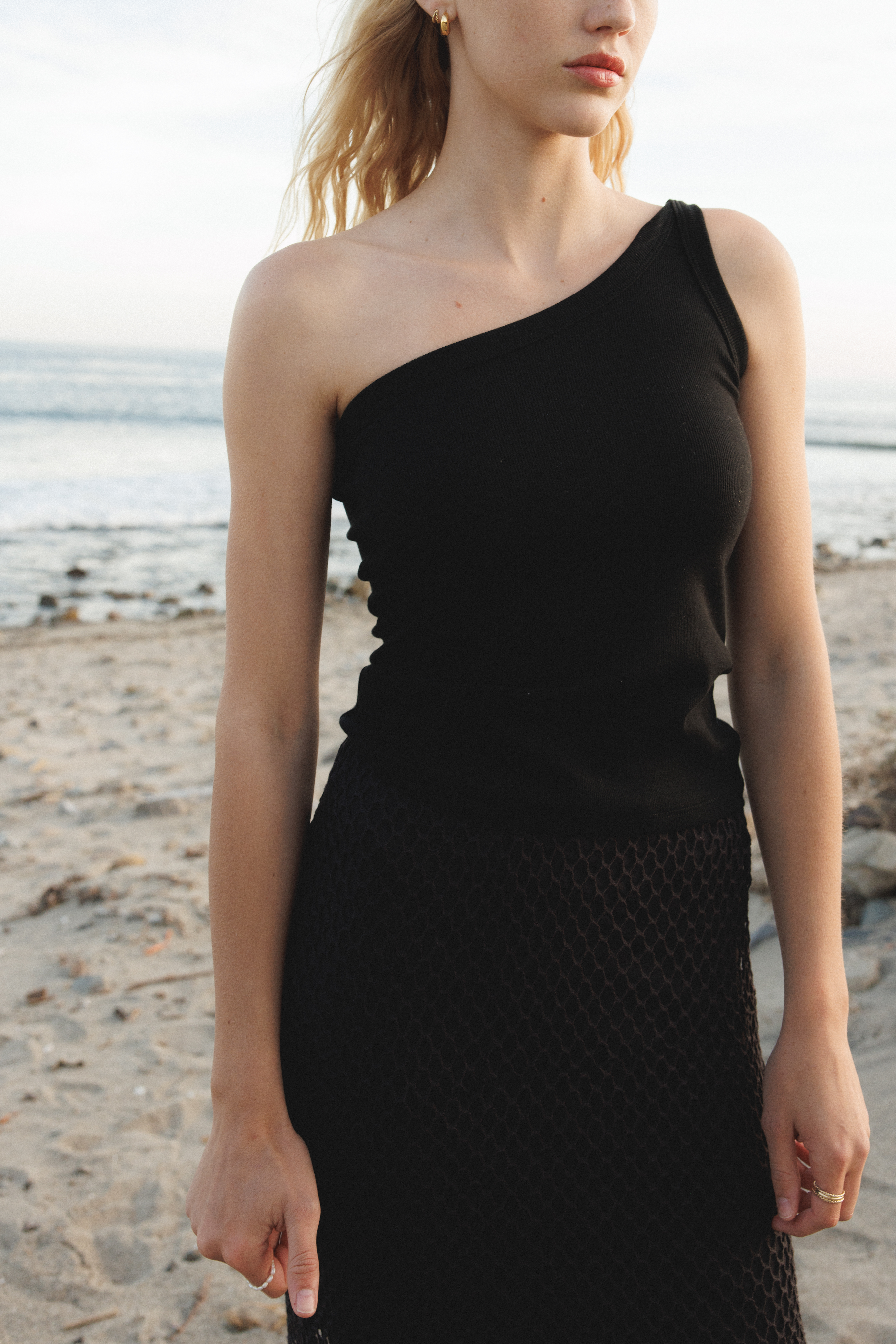 Female model wearing a sustainable asymmetrical one shoulder black top - VIR VITA
