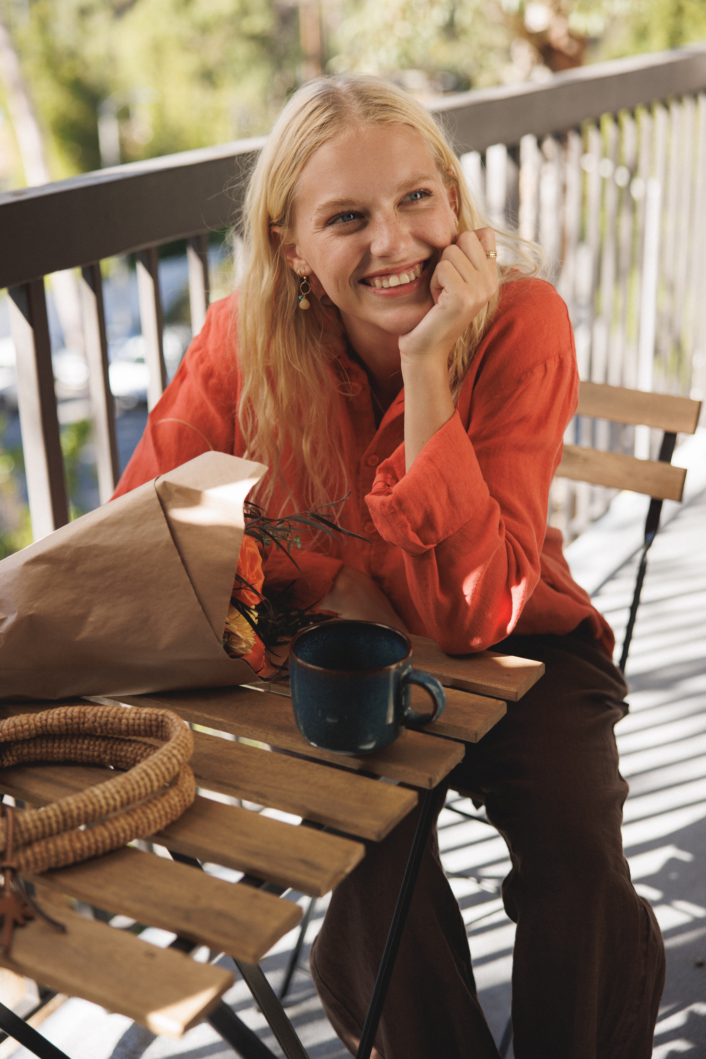 Female model, sitting on a balcony, wearing a cayenne / orange colored sustainable oversized linen button down long sleeve - VIR VITA
#color_cayenne