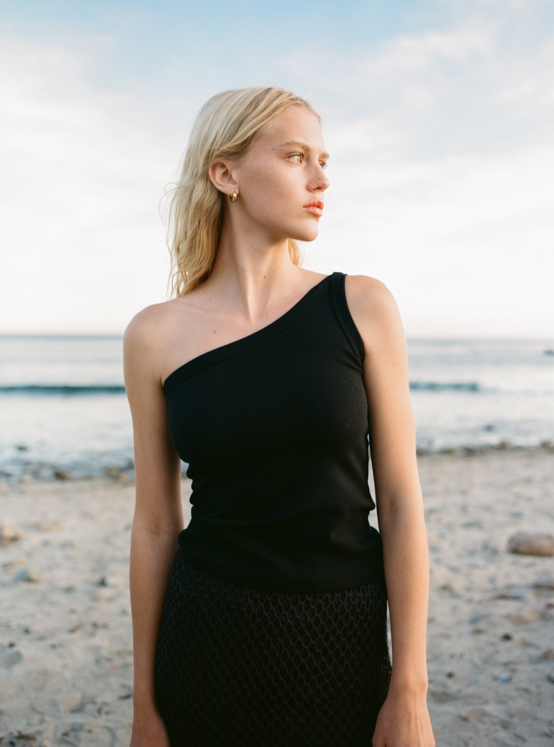 Female model wearing a sustainable asymmetrical one shoulder black top - VIR VITA
