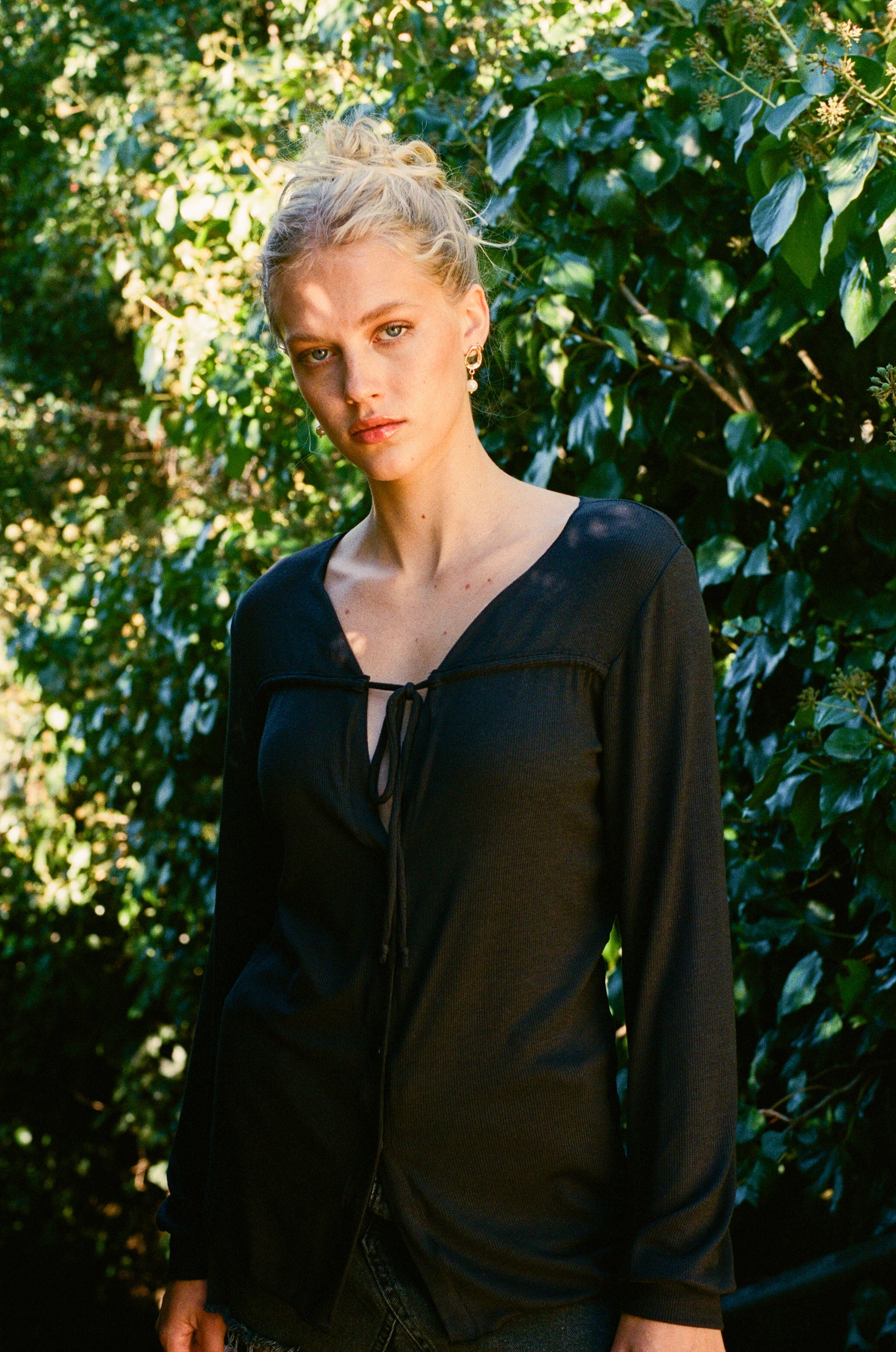 Female model wearing sustainable micro modal black buttery soft long sleeve ribbed top with tie and italian button. Romantic top, Classic, timeless, elegant, french style. natural organic clothing- VIR VITA

